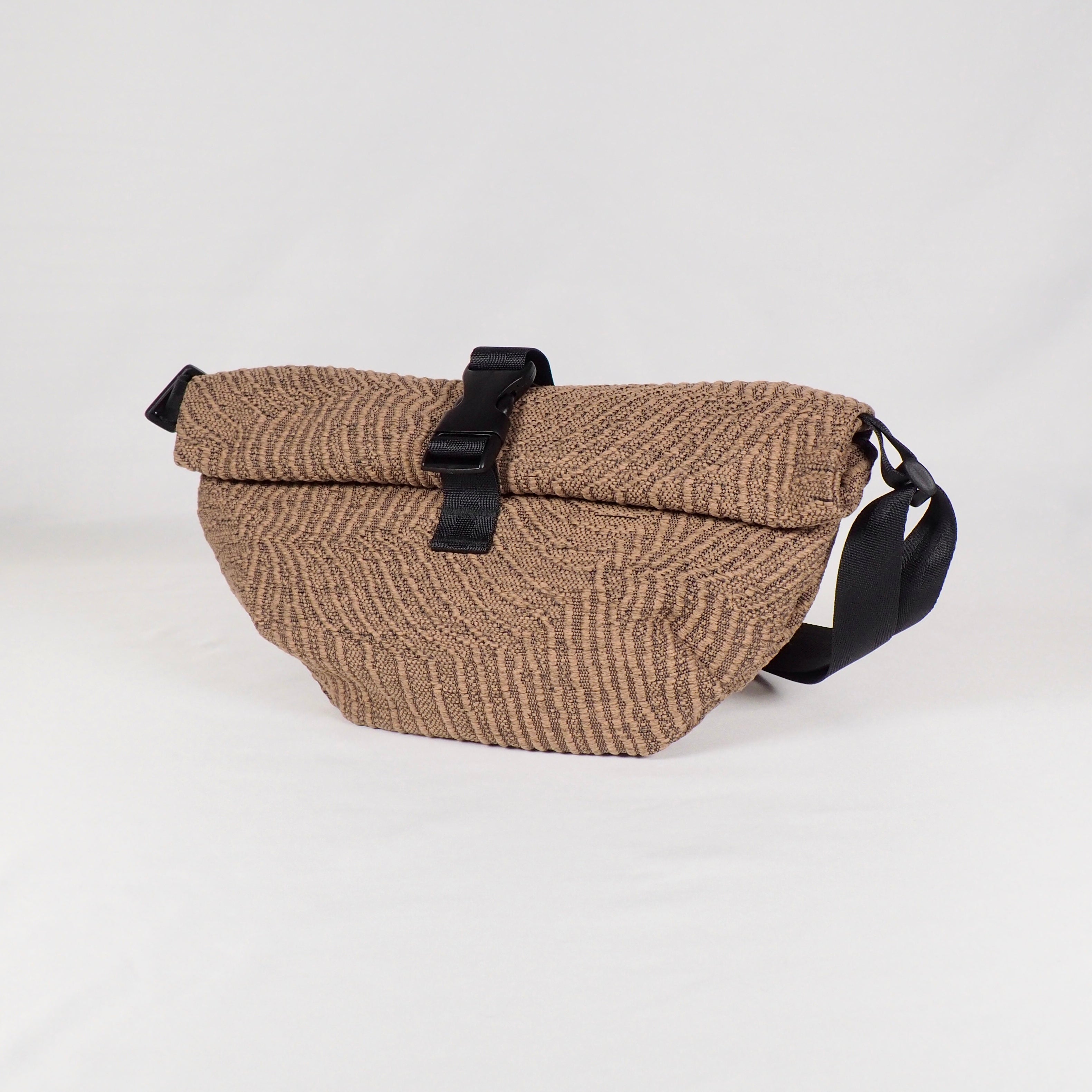 Braune Stricktasche mit Rolltop-Verschluss und schwarzem Riemen auf weißem Hintergrund.
