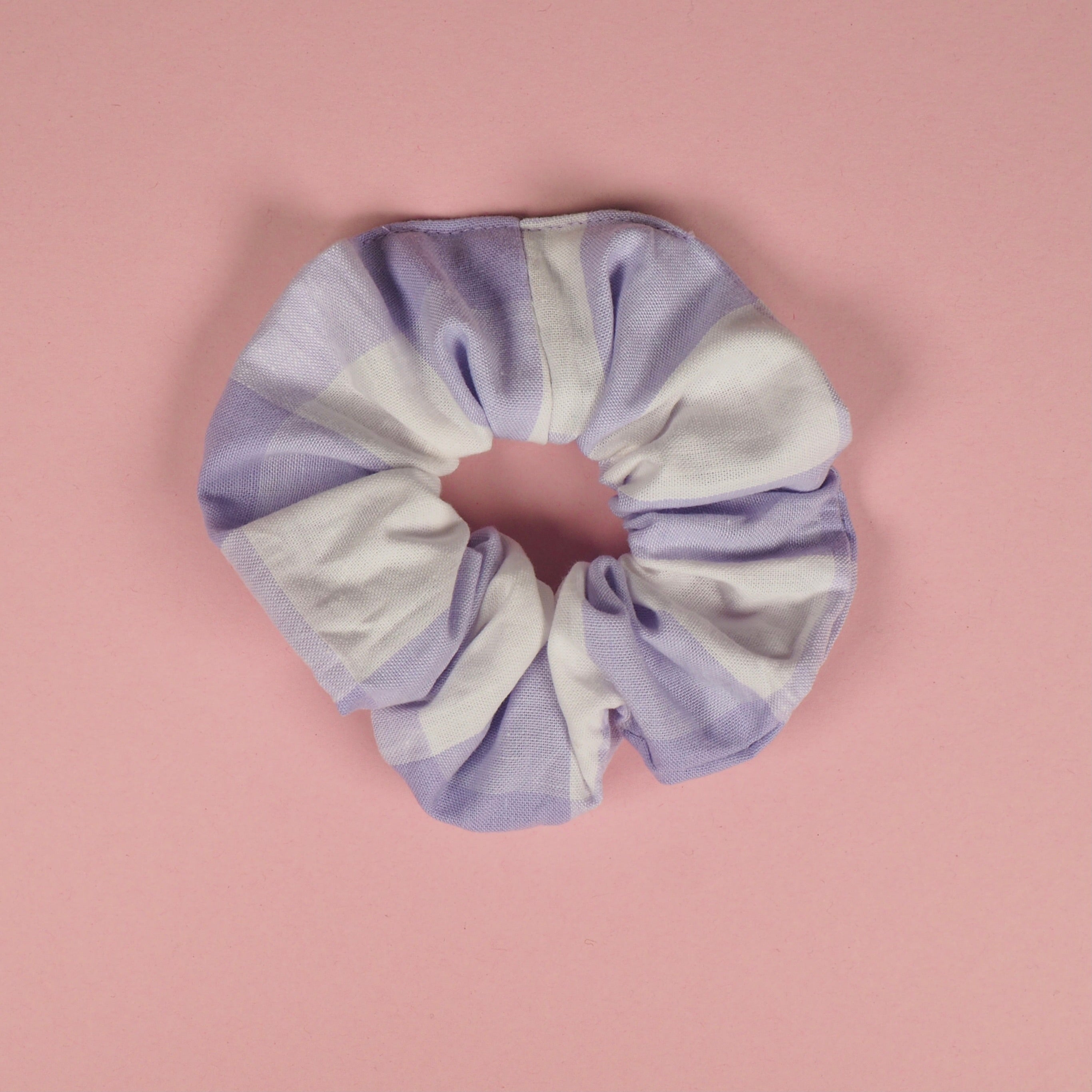 Lila-weiß gestreifter Haargummi auf rosa Hintergrund.