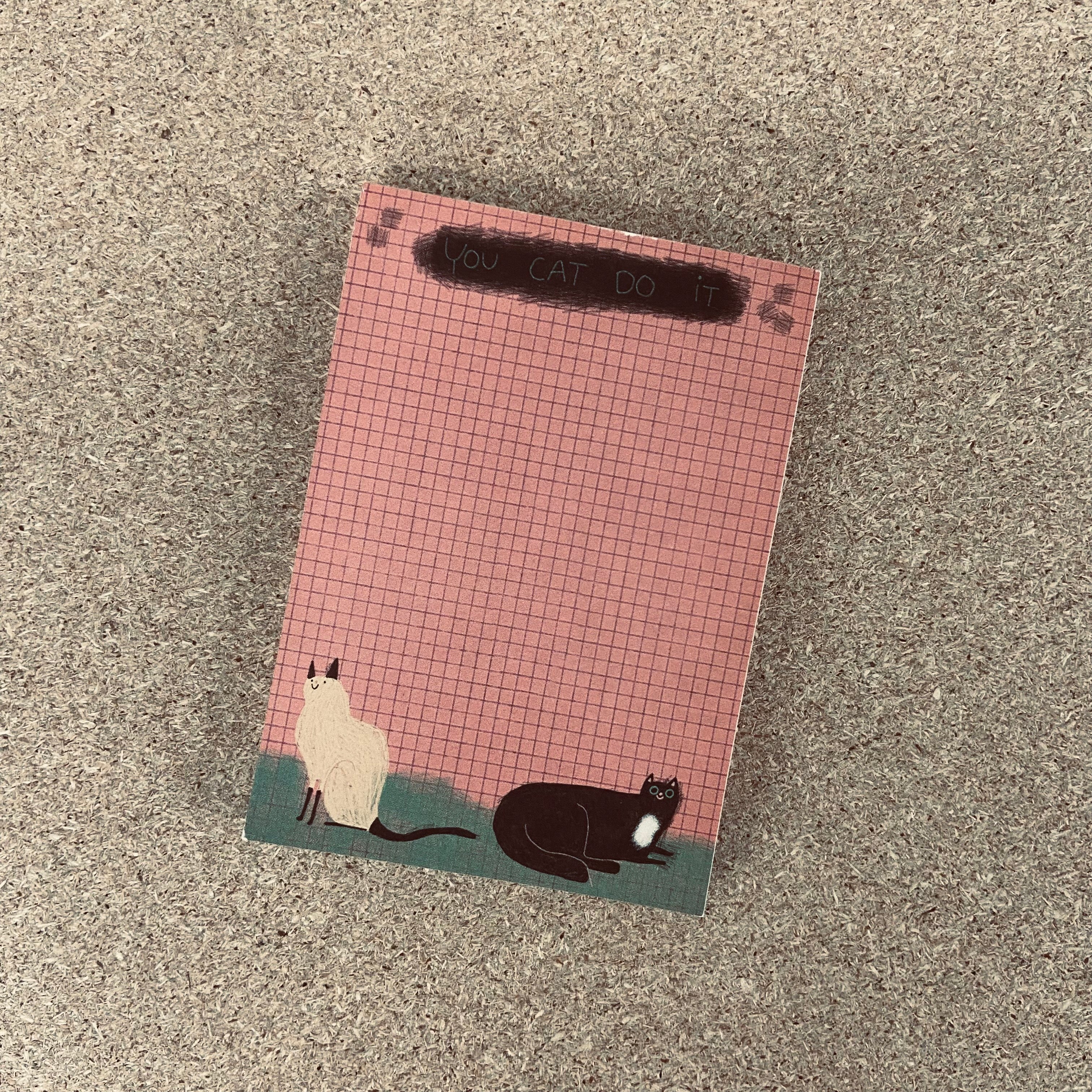 Notizblock mit kariertem Rosa und zwei Katzen am Rand, beschriftet mit "You cat do it".