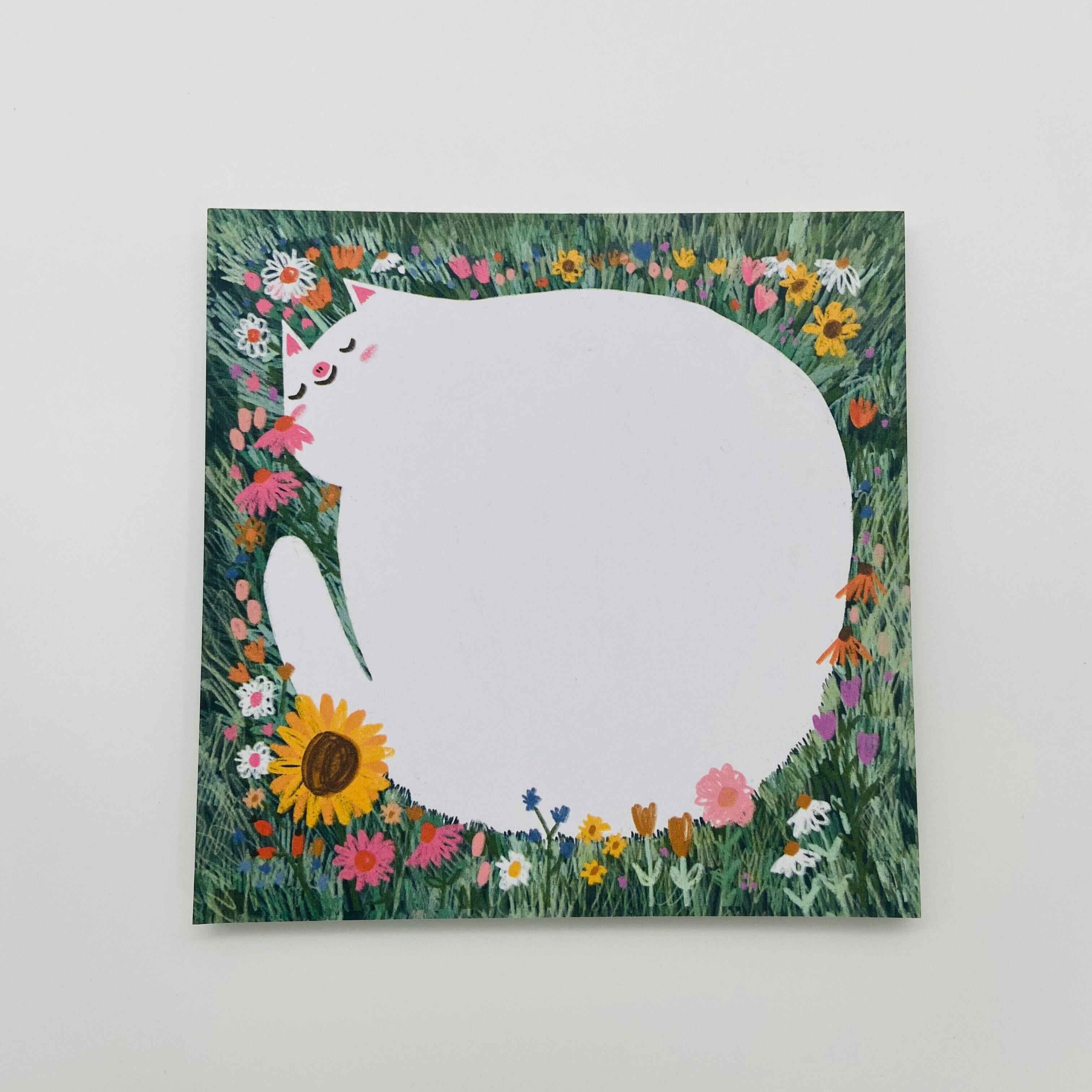 Illustration einer weißen Katze, die von bunten Blumen umgeben ist, auf grünem Hintergrund.