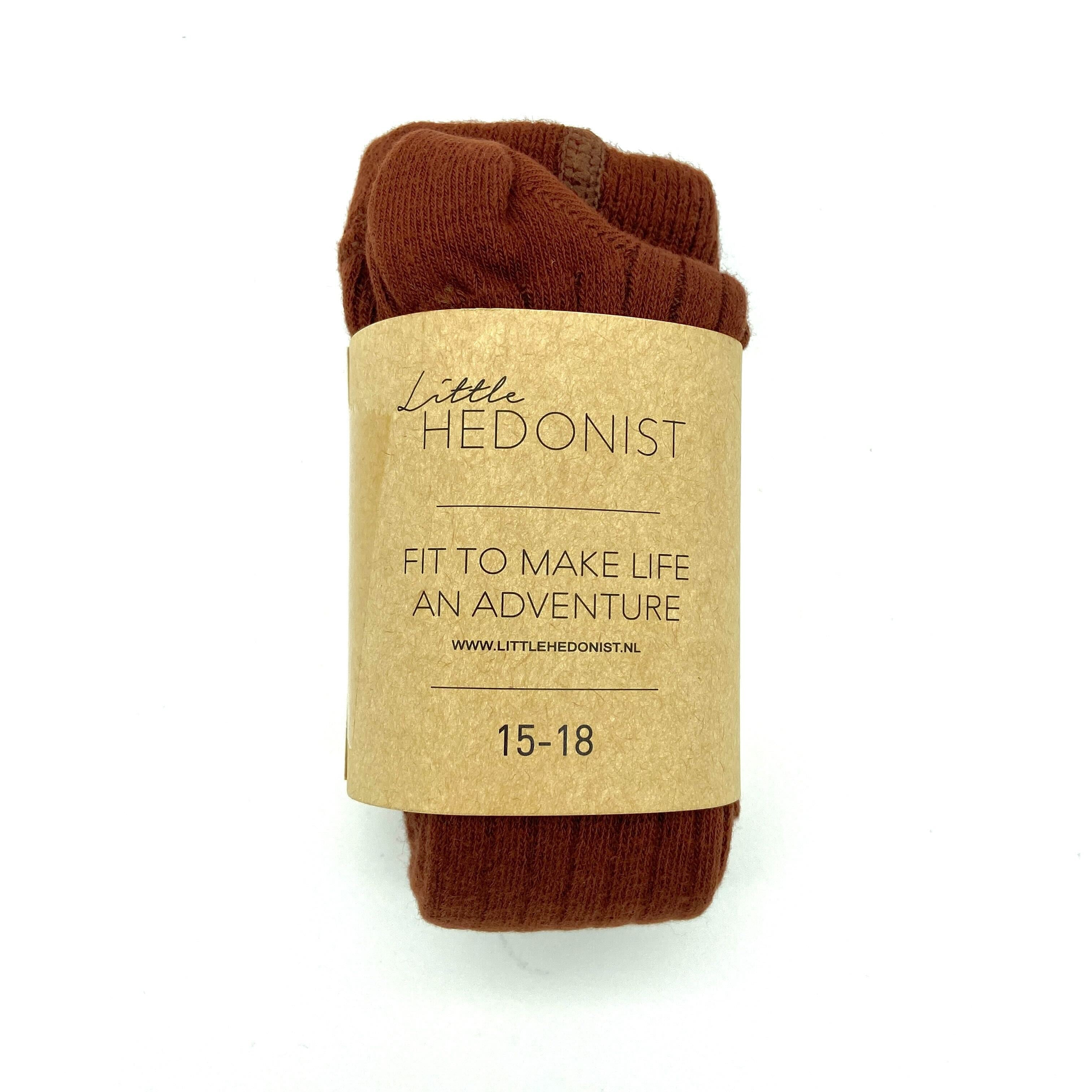 Ein Paar braune Socken, eingewickelt in ein Kraftpapieretikett mit der Aufschrift: Little HEDONIST, FIT TO MAKE LIFE AN ADVENTURE, www.littlehedonist.nl, 15-18.