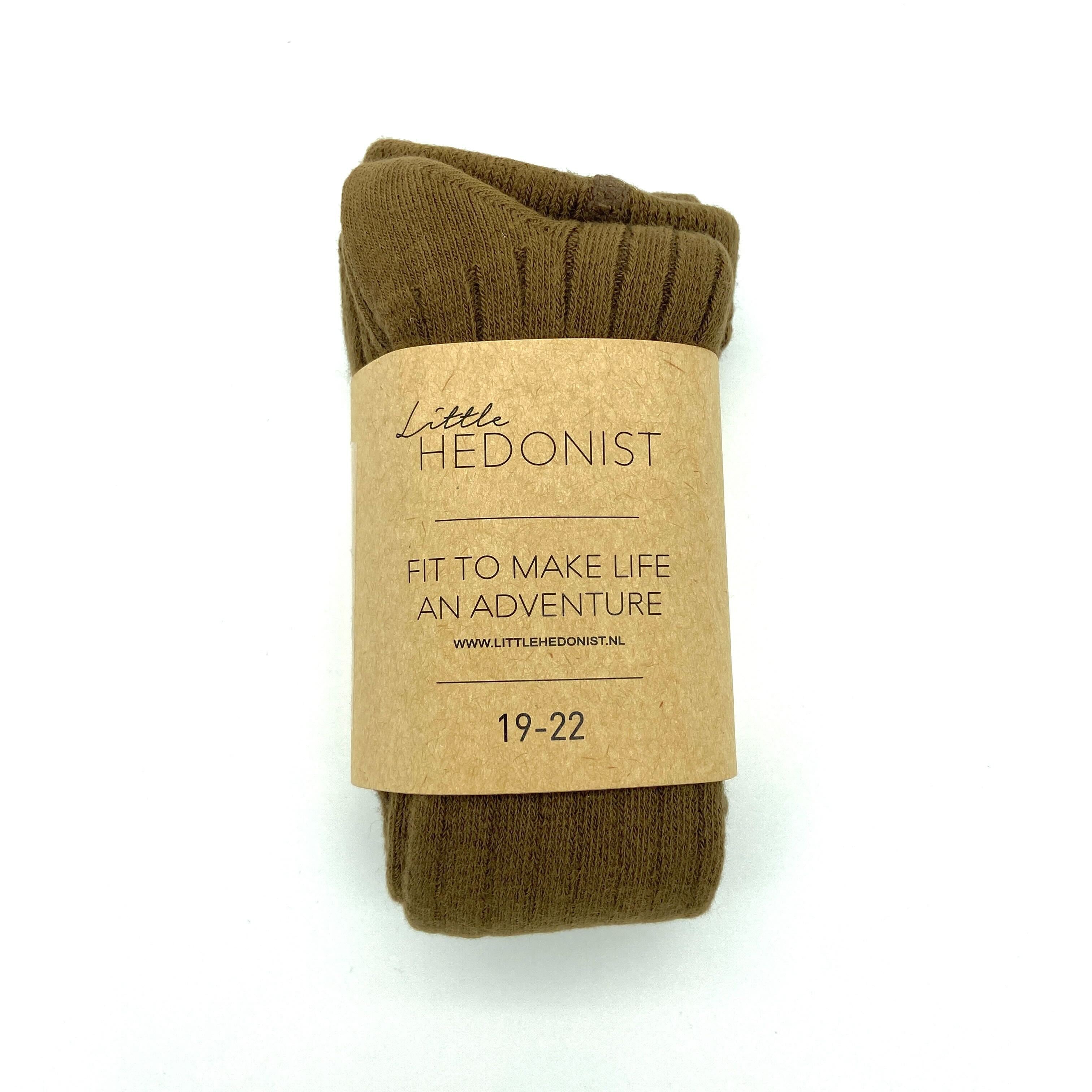 Ein Paar brauner Socken ist aufgerollt und mit einem Kraftpapieretikett mit der Aufschrift Little Hedonist, Fit to make life an adventure, 19-22, www.littlehedonist.nl vor weißem Hintergrund verpackt.
