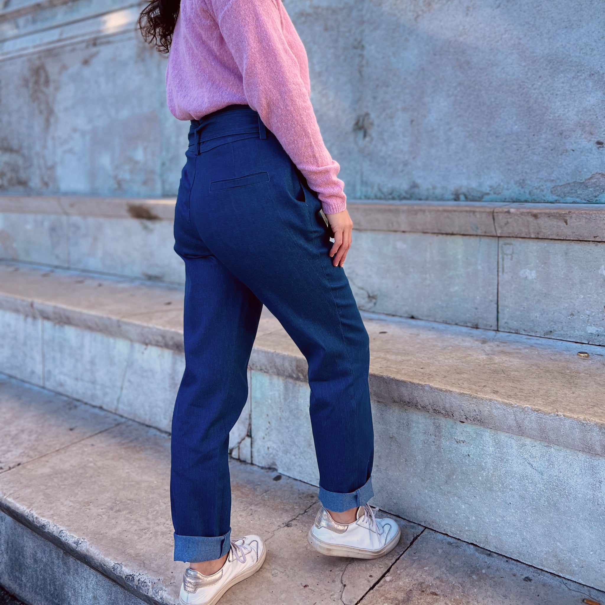 Person mit rosa Pullover und blauer Hose geht eine Steintreppe hinauf.