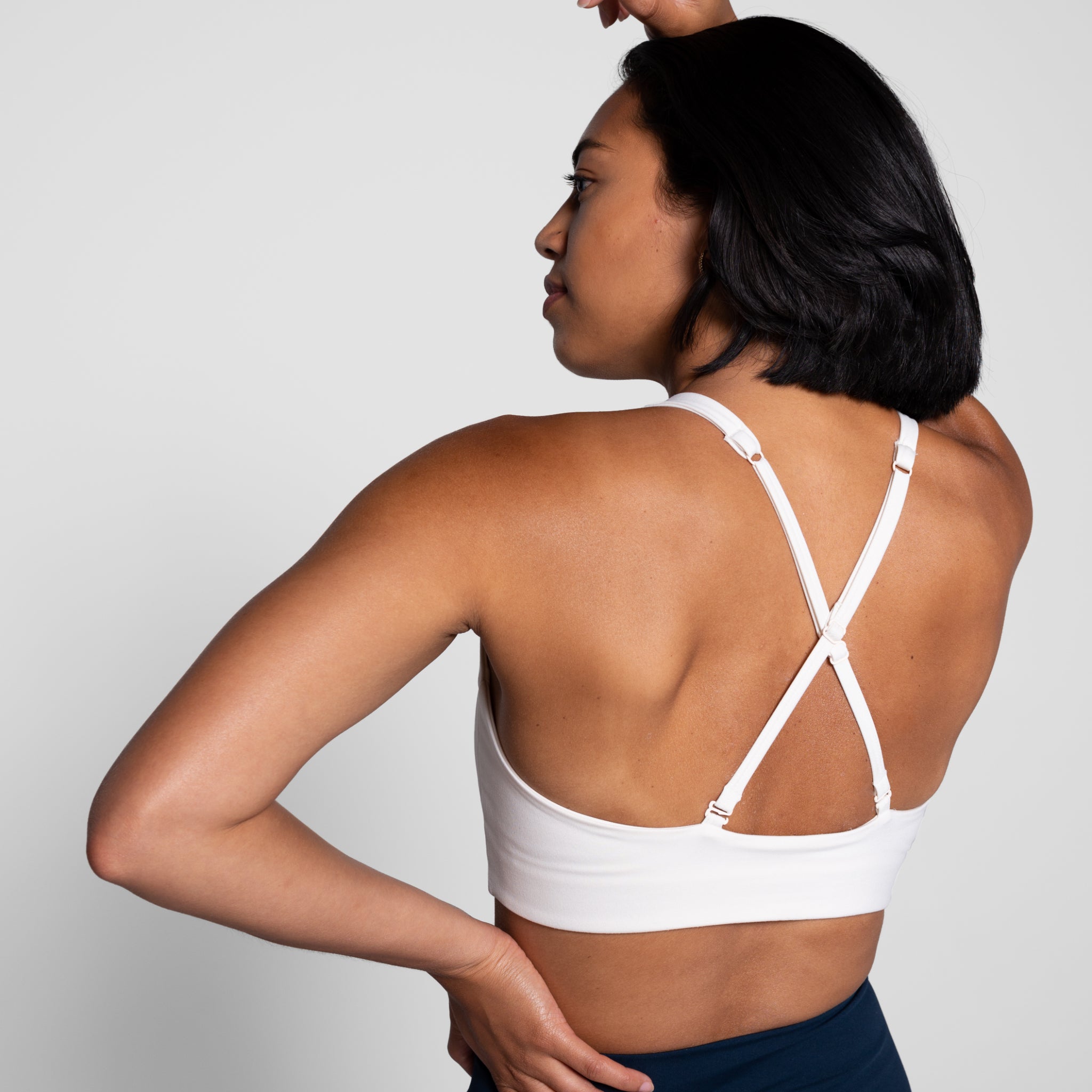 Person in weißem Sport-BH von hinten, zeigt Kreuzträger-Design.