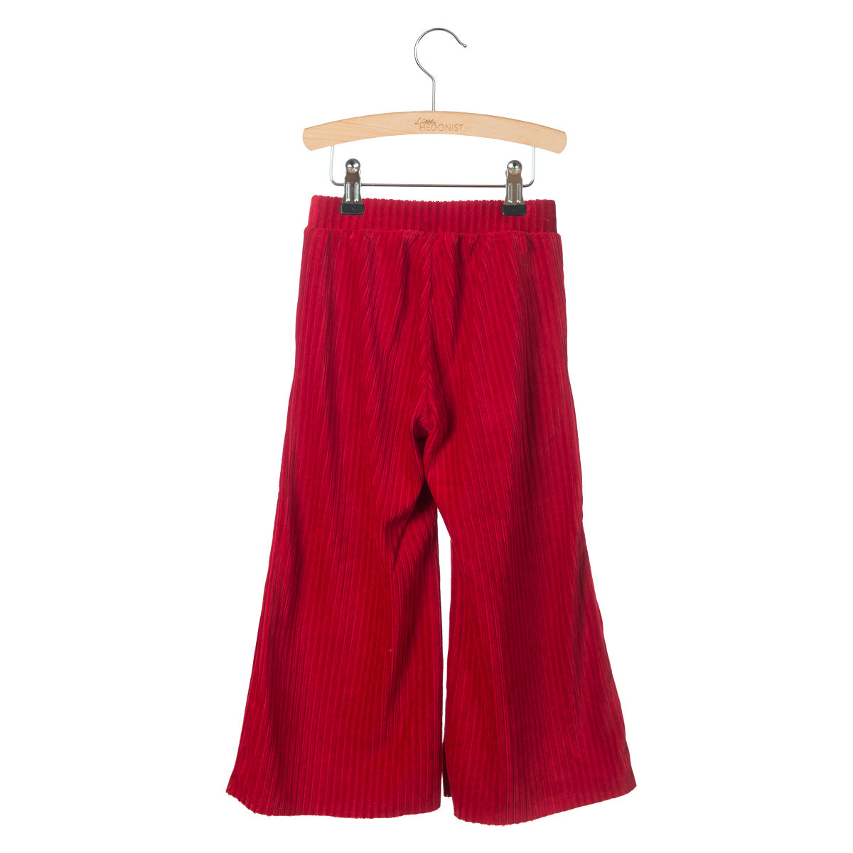 Eine rote Cordhose mit weiten Beinen hängt auf einem Holzbügel vor einem weißen Hintergrund.
