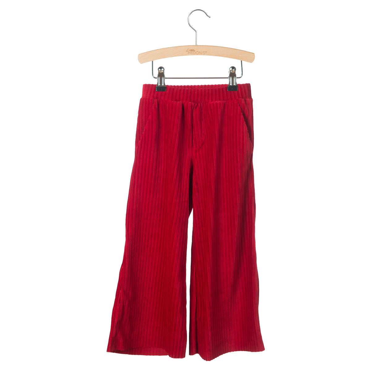 Rote Cordhose mit weitem Bein und elastischem Bund, aufgehängt an einem Holzbügel mit Klammern vor weißem Hintergrund.
