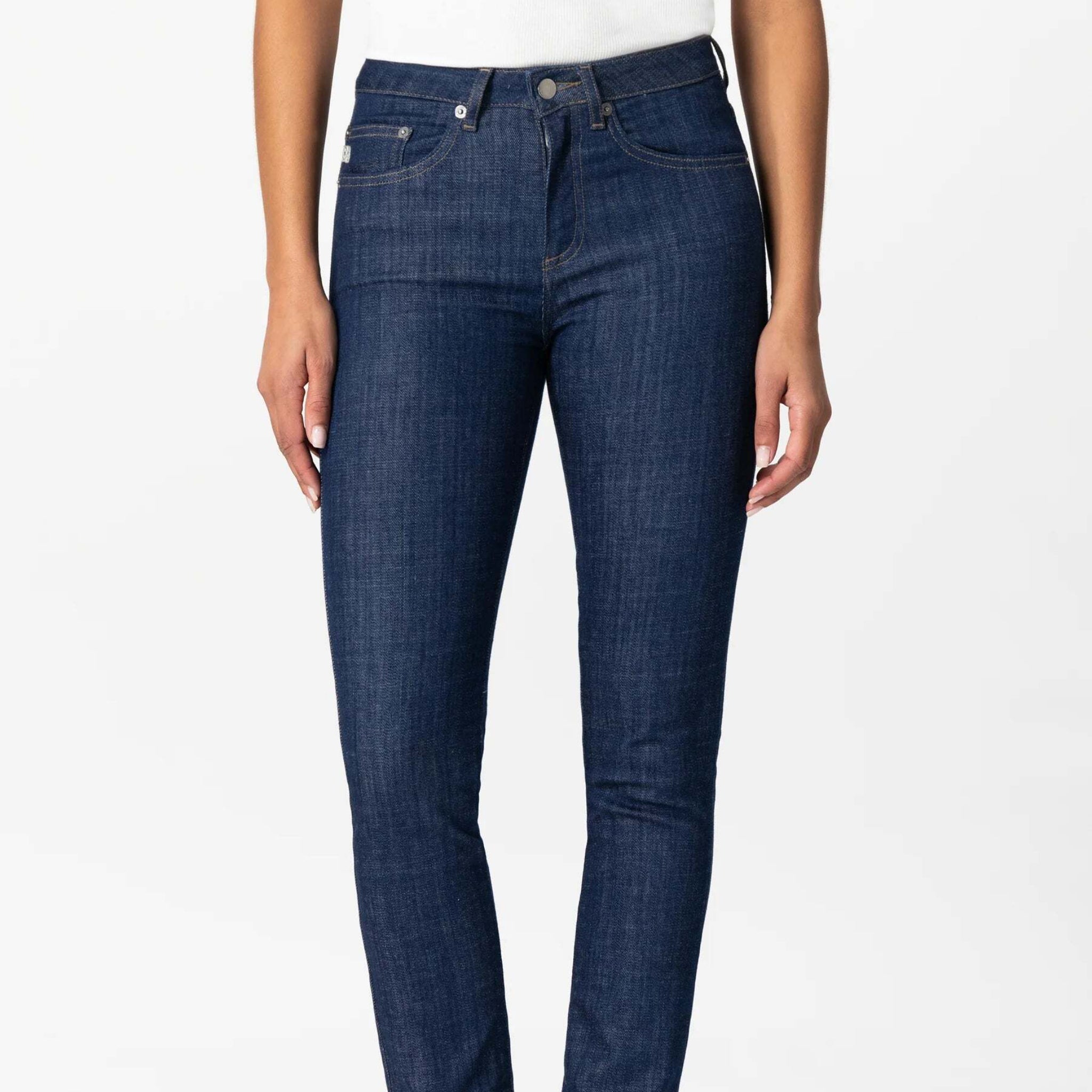 Person trägt dunkelblaue Jeans und ein weißes Oberteil vor weißem Hintergrund.