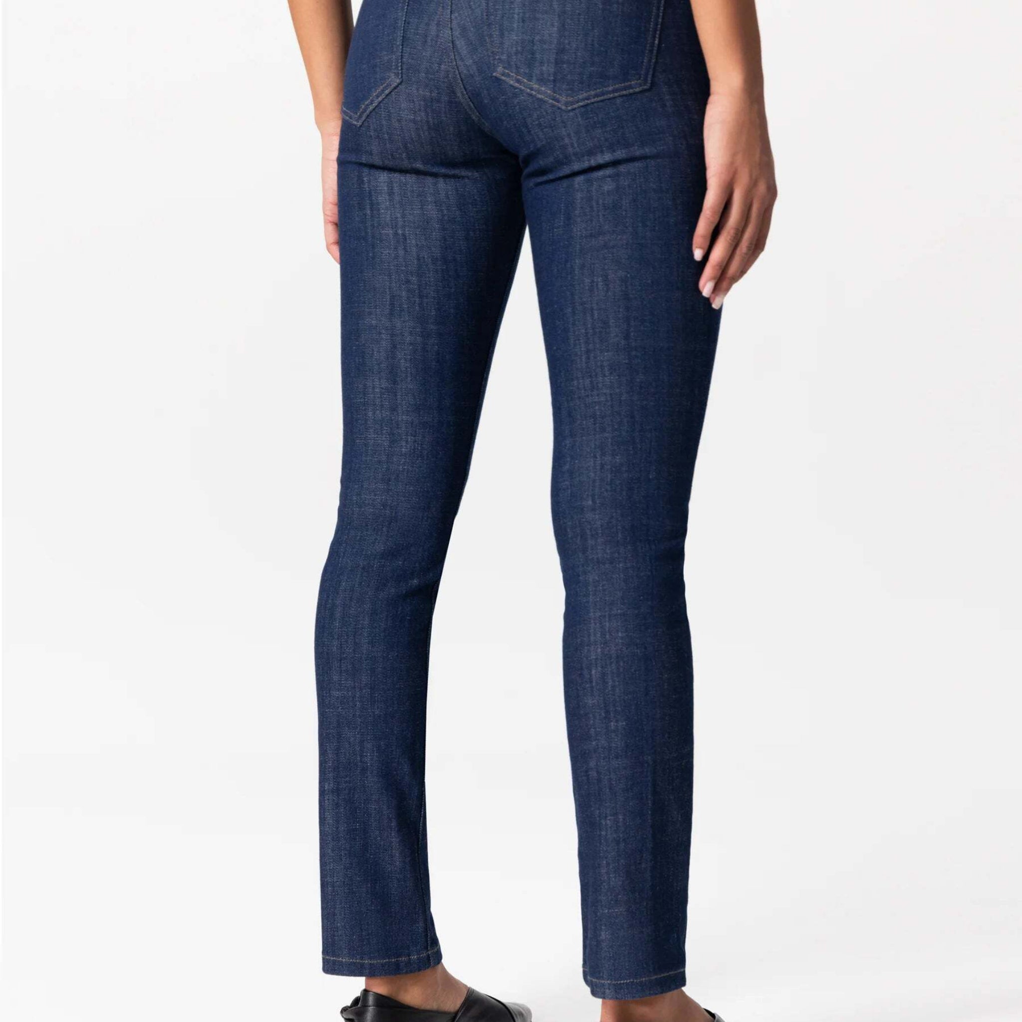 Person in dunkelblauer Jeans, von hinten fotografiert, mit schwarzem Schuh.