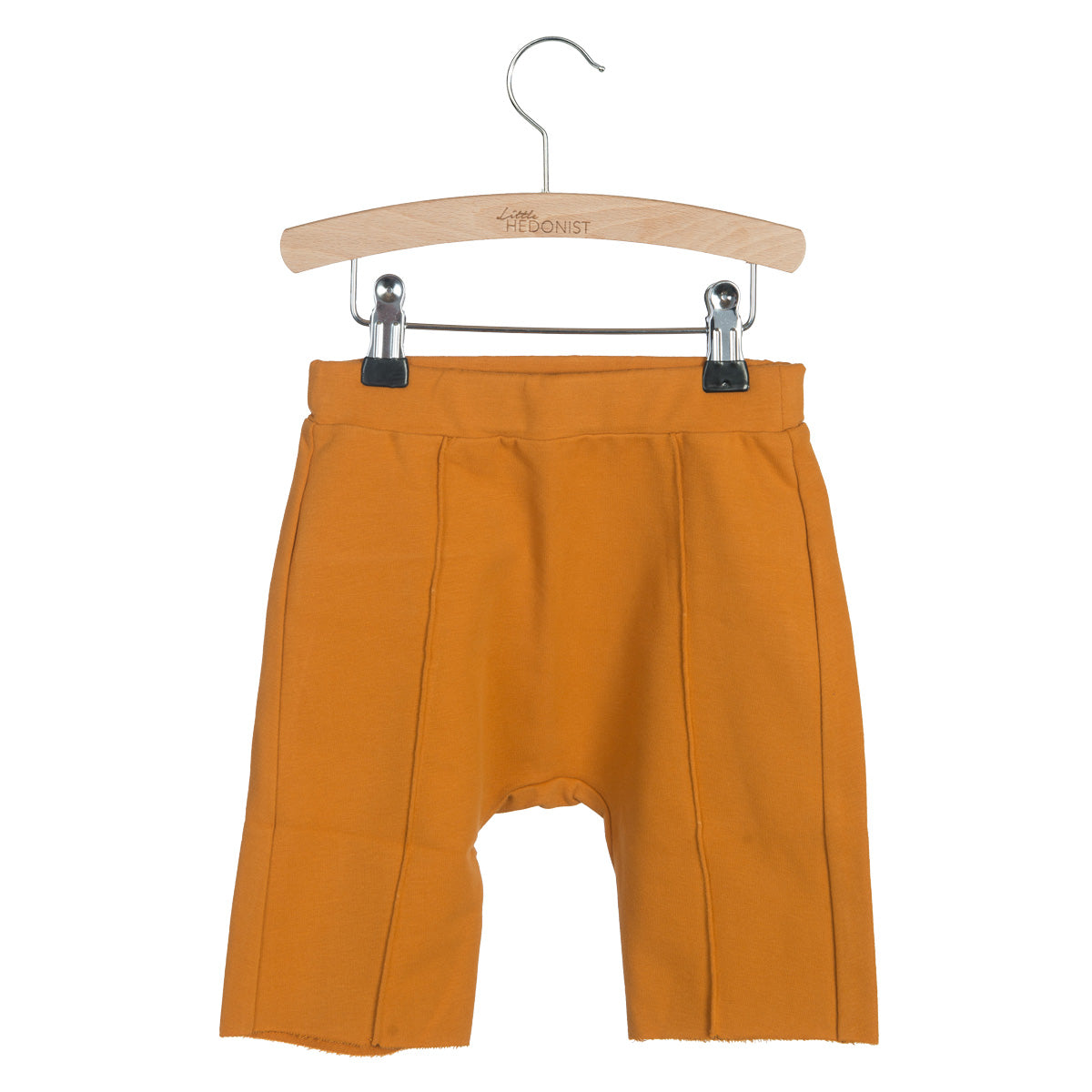 Orangefarbene Shorts für Kleinkinder mit sichtbaren Nähten hängen auf einem Holzbügel vor einem weißen Hintergrund. Die Shorts haben eine lockere Passform und unfertige Säume an den Beinen.