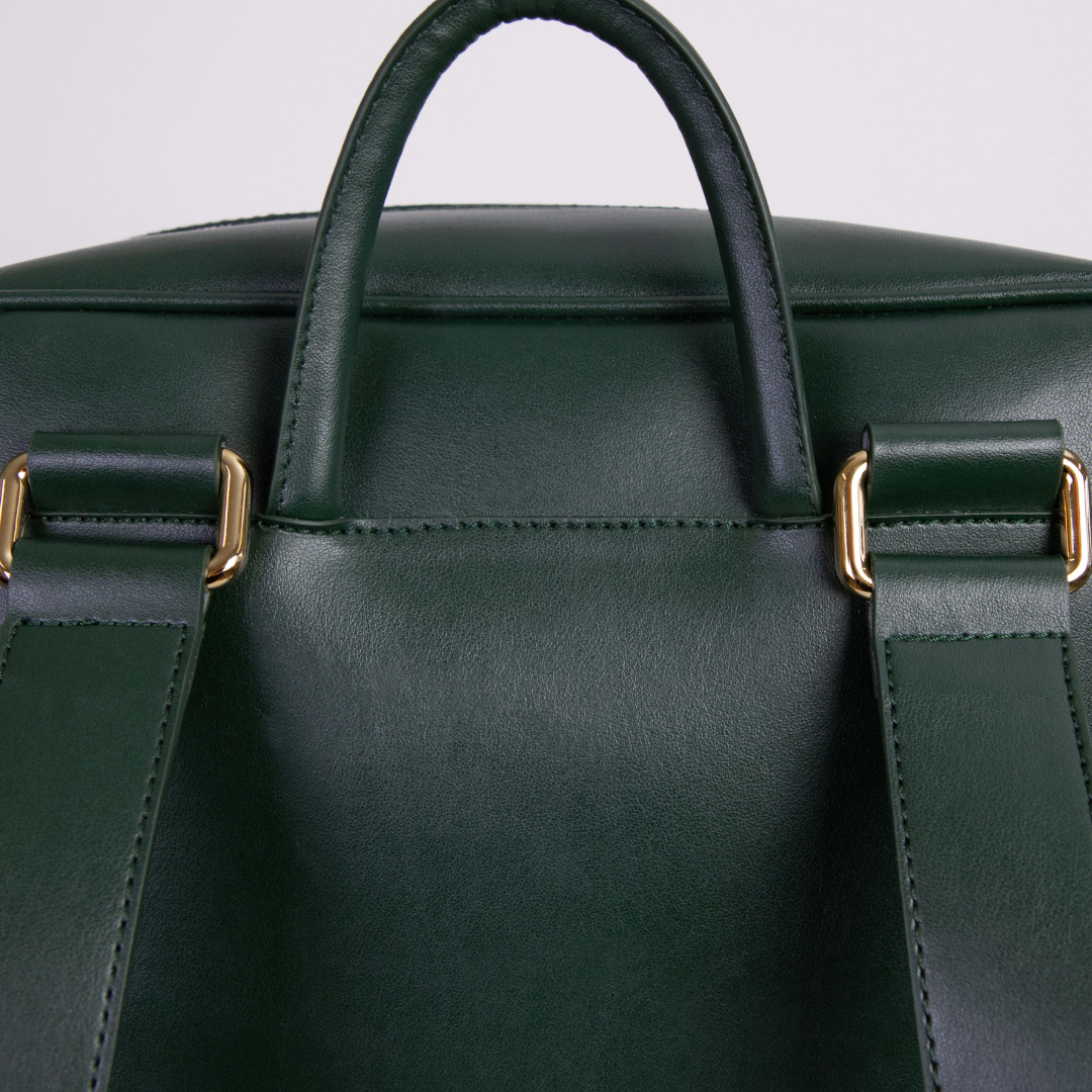 Dunkelgrüner Lederrucksack mit goldenen Schnallen und einem Tragegriff.