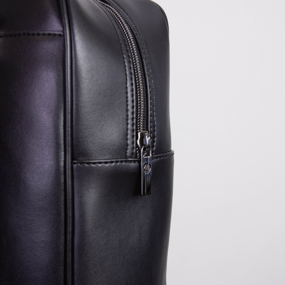 Nahaufnahme eines schwarzen Lederrucksacks mit silbernem Reißverschluss.