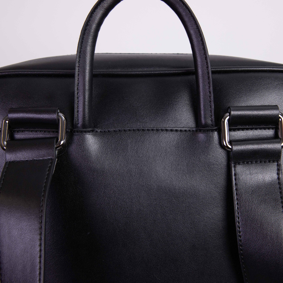 Nahaufnahme einer schwarzen Ledertasche mit Trageriemen und silberner Metallschließe.