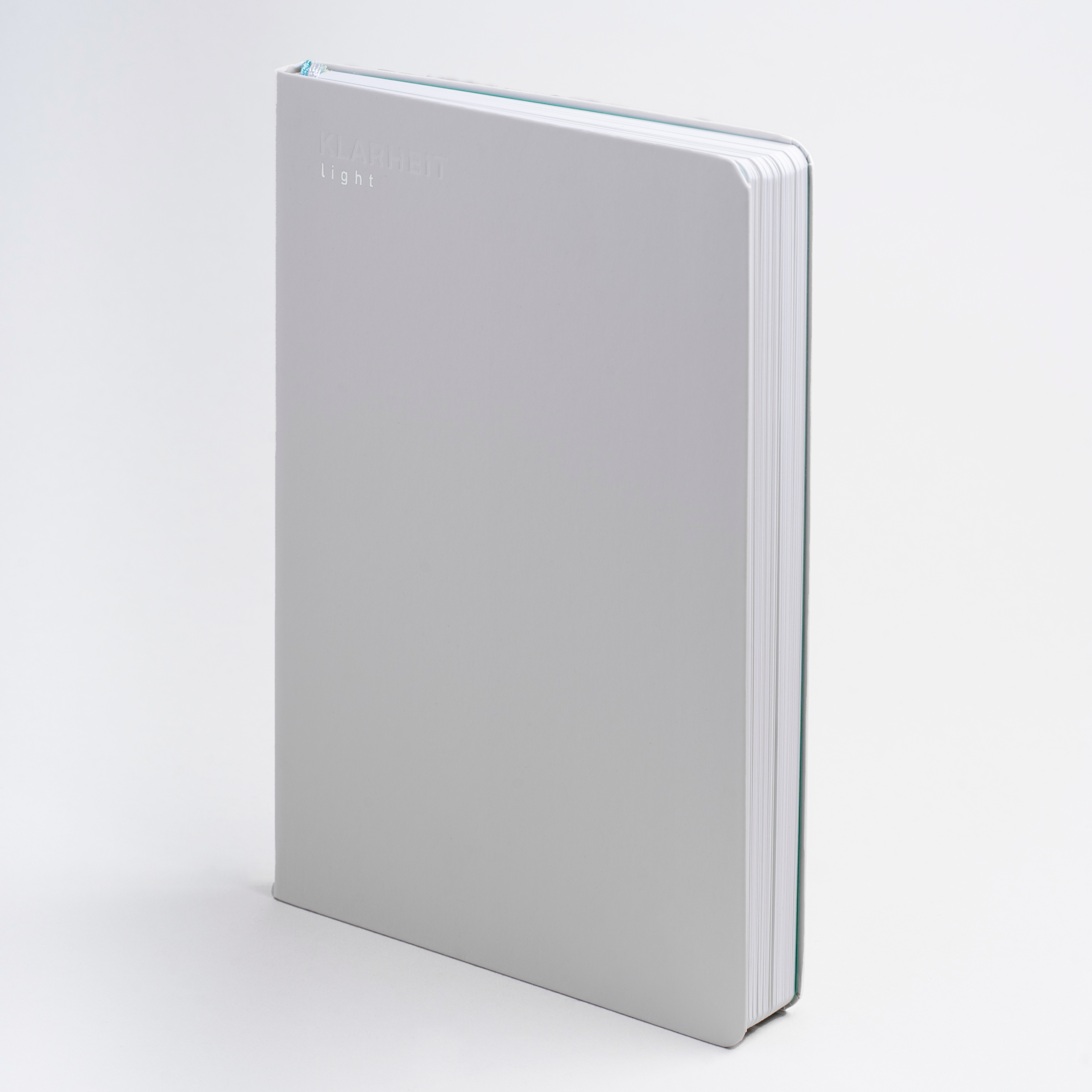 Graues Notizbuch mit der Aufschrift "KLARHEIT light" auf dem Cover, leicht angewinkelt fotografiert.