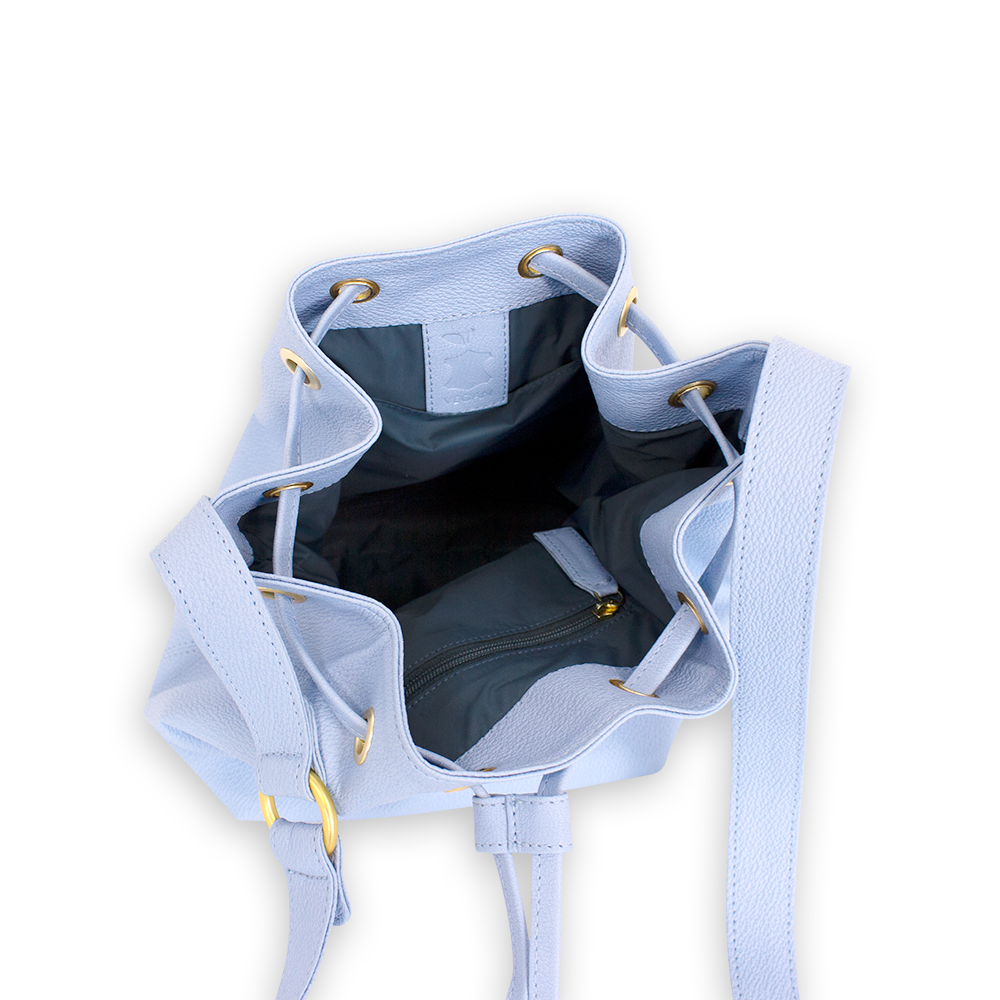 Innenansicht einer hellblauen Ledertasche mit goldenen Ösen, schwarzen Fächern und einem Reißverschluss im Inneren.