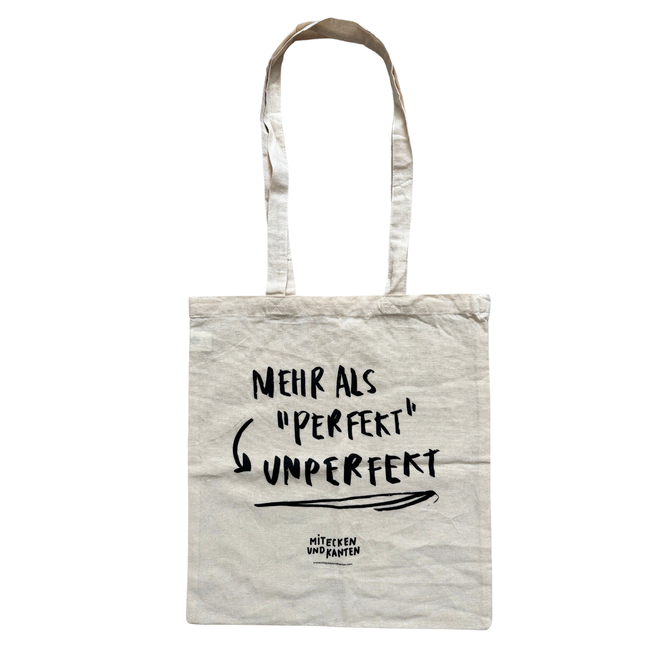 Stofftasche mit der Aufschrift: "Mehr als 'perfekt', unperfekt. Mit Ecken und Kanten" in schwarzer Schrift.