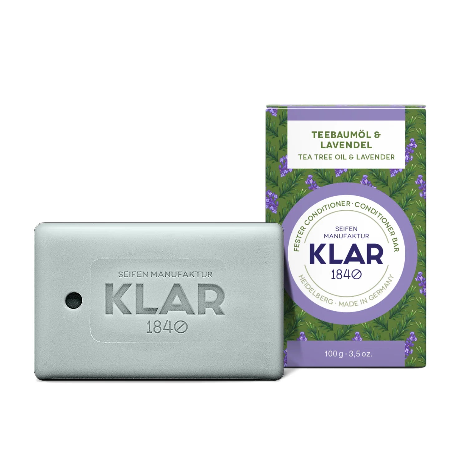 Ein rechteckiger Riegel Klar 1840 Conditioner befindet sich neben der Schachtel, die mit Lavendelbildern verziert ist und auf der Teebaumöl & Lavendel in Deutsch und Englisch steht.