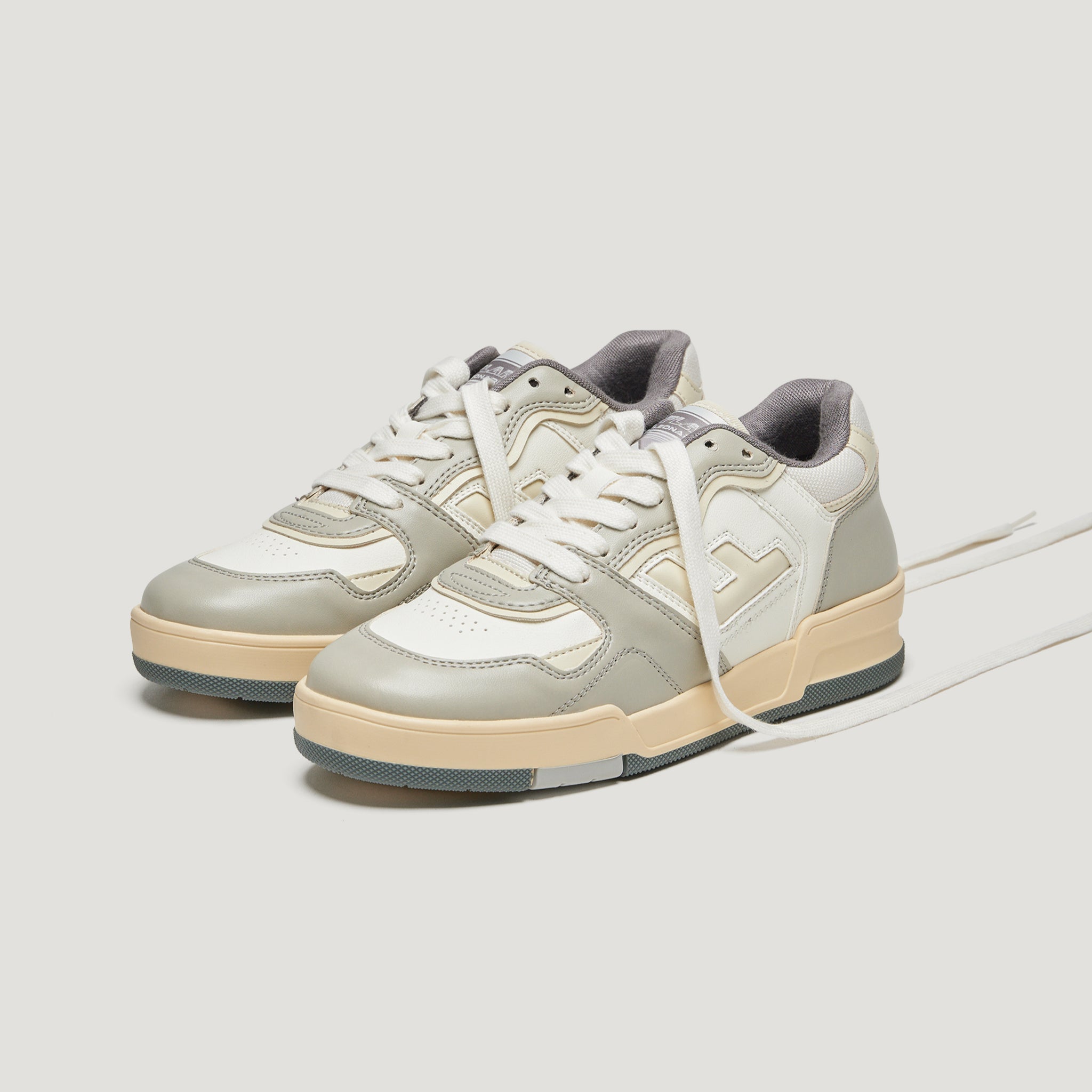 Ein Paar weiße und graue Sneakers mit beigen Sohlen auf weißem Hintergrund.