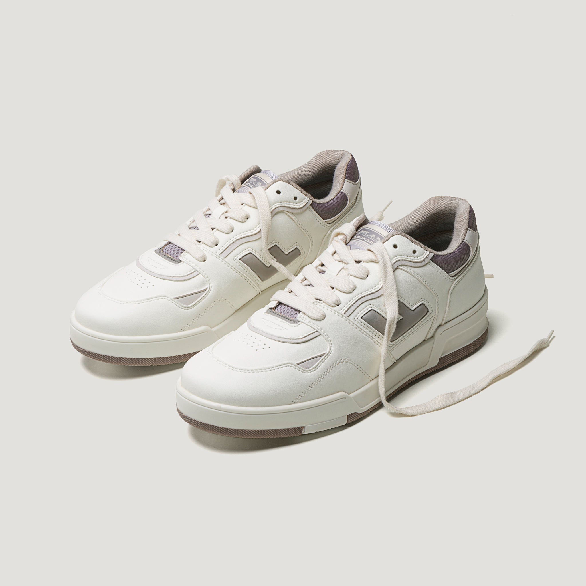 Weiße Turnschuhe mit grauen und beigen Details auf einem hellgrauen Hintergrund. Ein Schnürsenkel ist nicht gebunden.