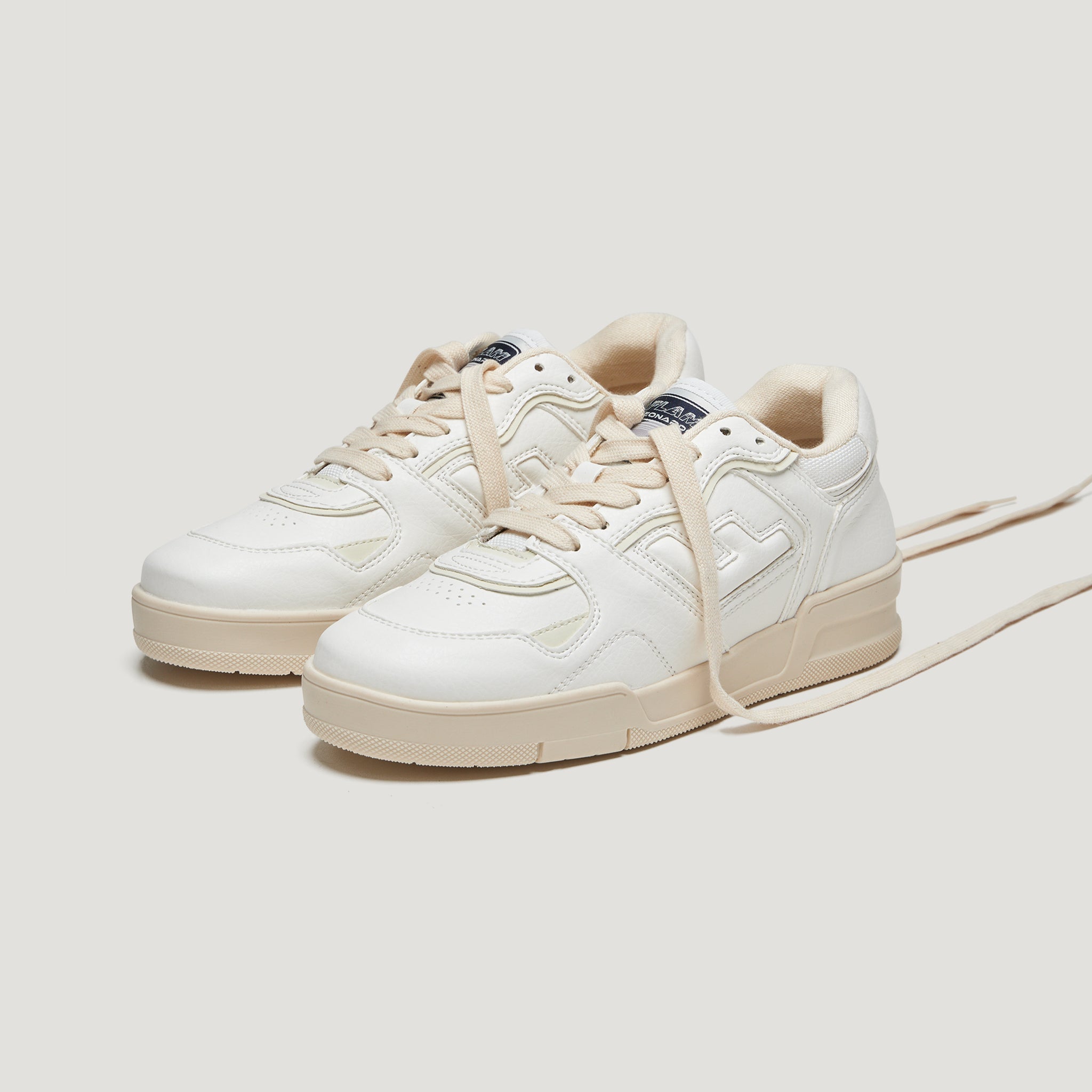 Weiße Turnschuhe mit beigen Schnürsenkeln auf einem hellen Hintergrund.