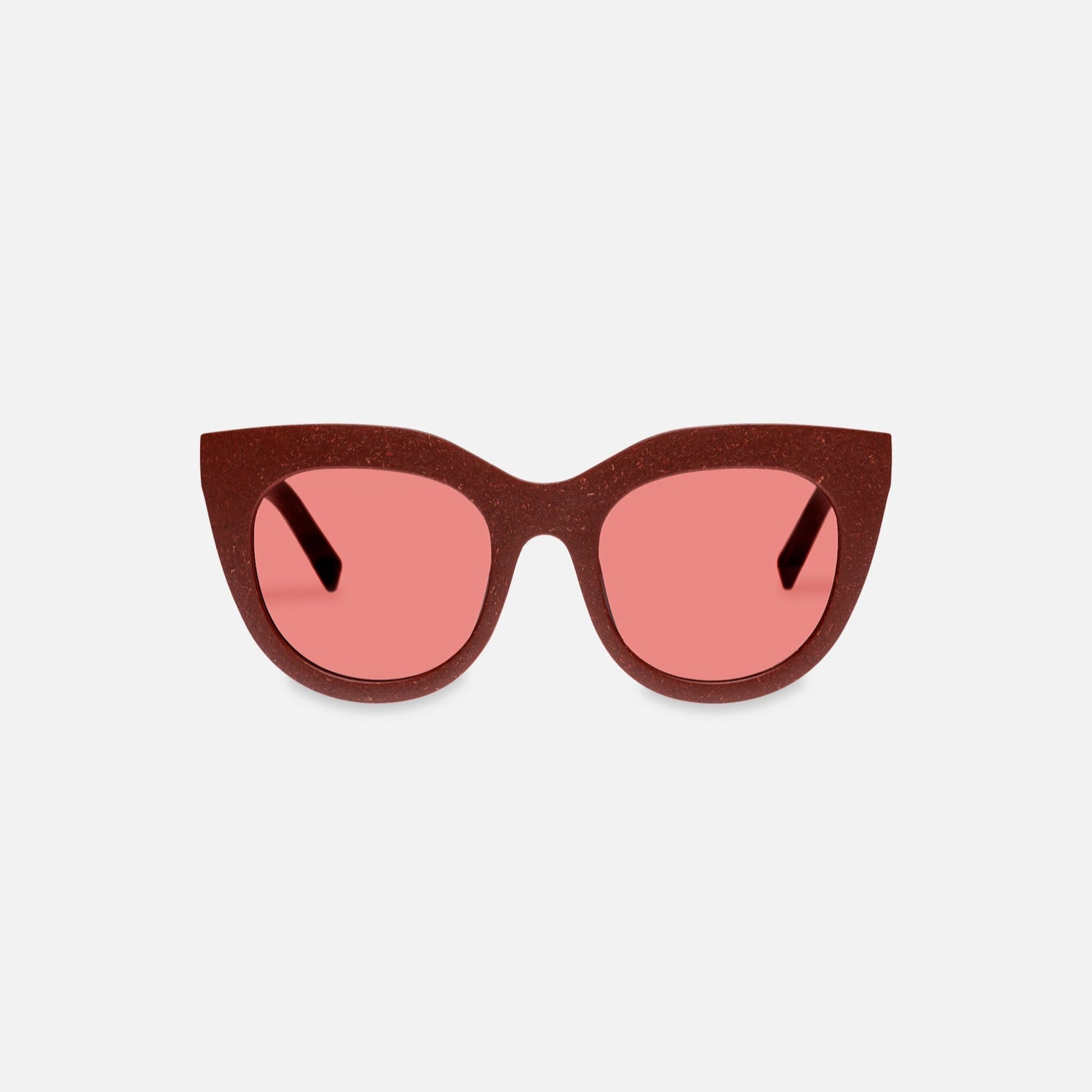 Eine Cat-Eye-Sonnenbrille mit dunkelrotem, glitzerndem Rahmen und rosa getönten Gläsern vor einem schlichten weißen Hintergrund.