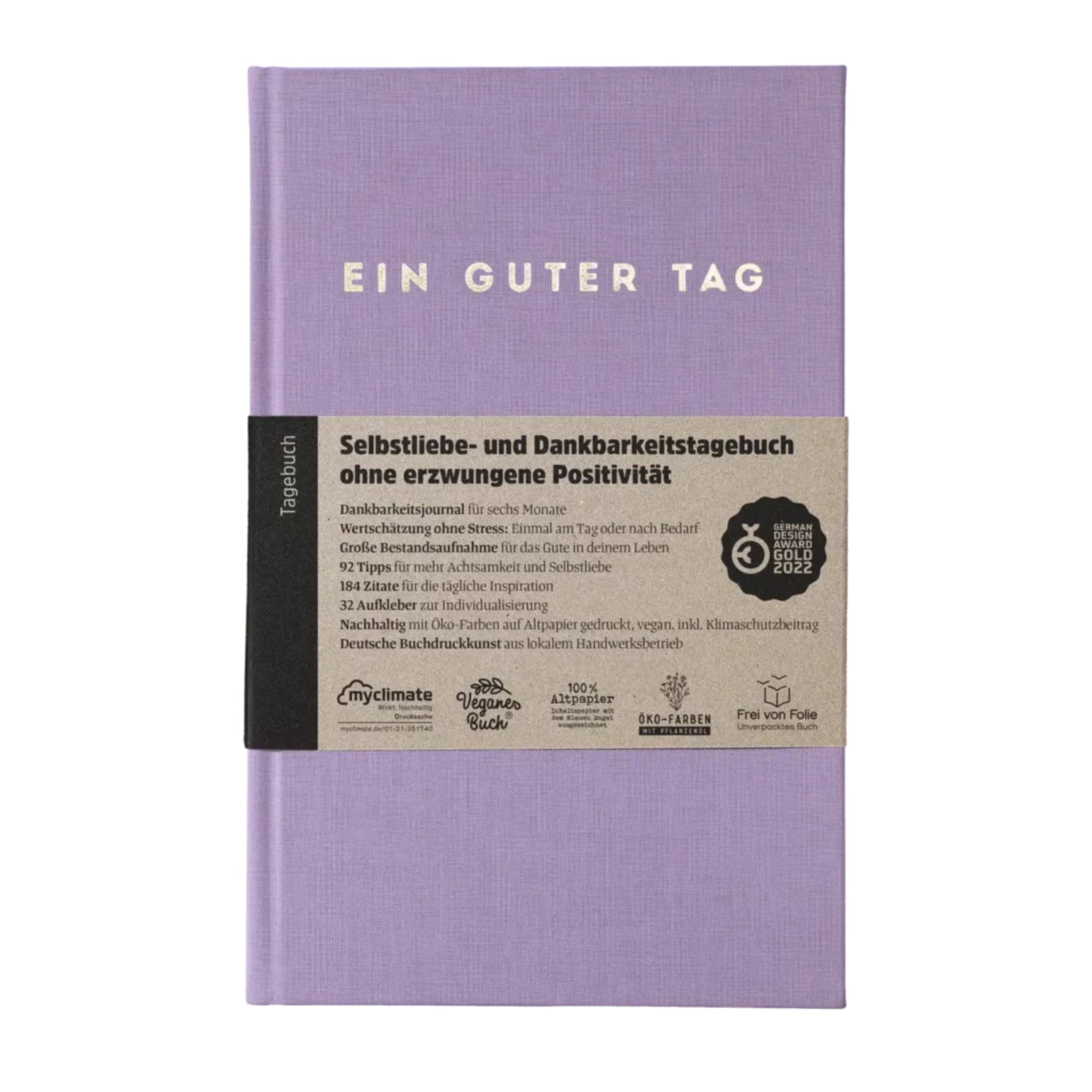 Lila Tagebuch mit der Aufschrift „Ein guter Tag“ und einem Etikett für Selbstliebe und Dankbarkeit ohne erzwungene Positivität.