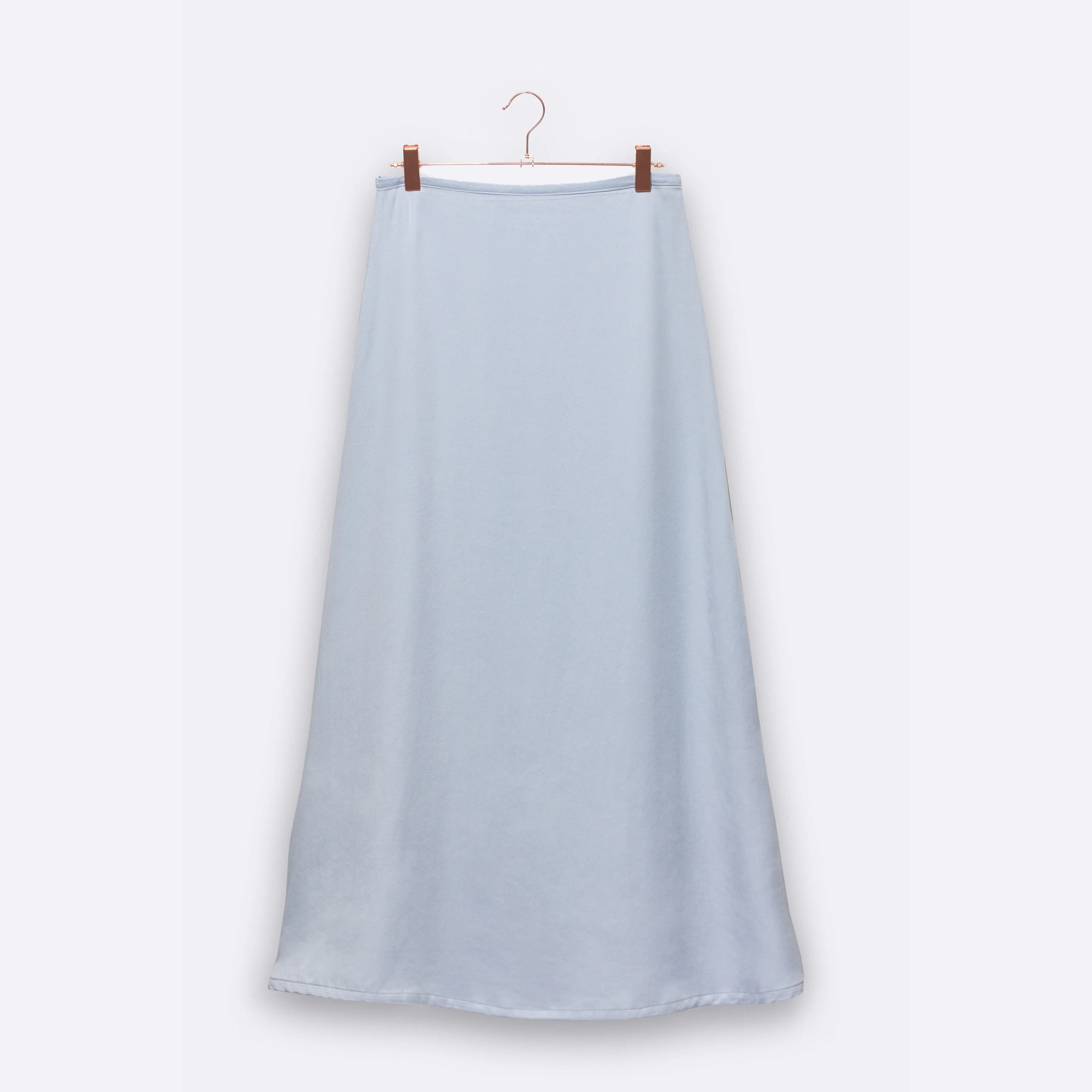 Ein langer, hellblauer Rock hängt an einem Kleiderbügel vor einem neutralen Hintergrund.