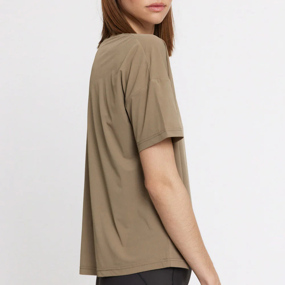 Frau in beigefarbenem T-Shirt im Profil vor neutralem Hintergrund.