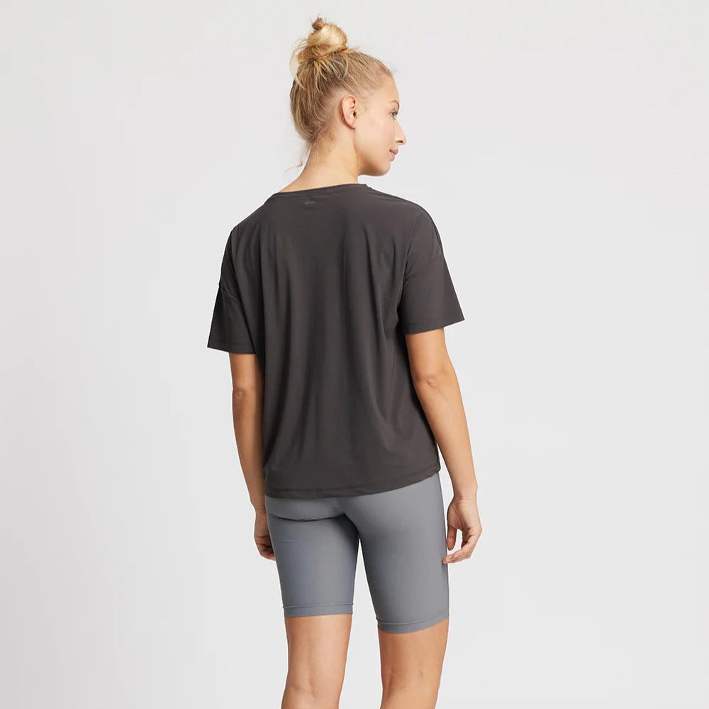 Frau von hinten in einem dunkelgrauen T-Shirt und hellgrauen Shorts.