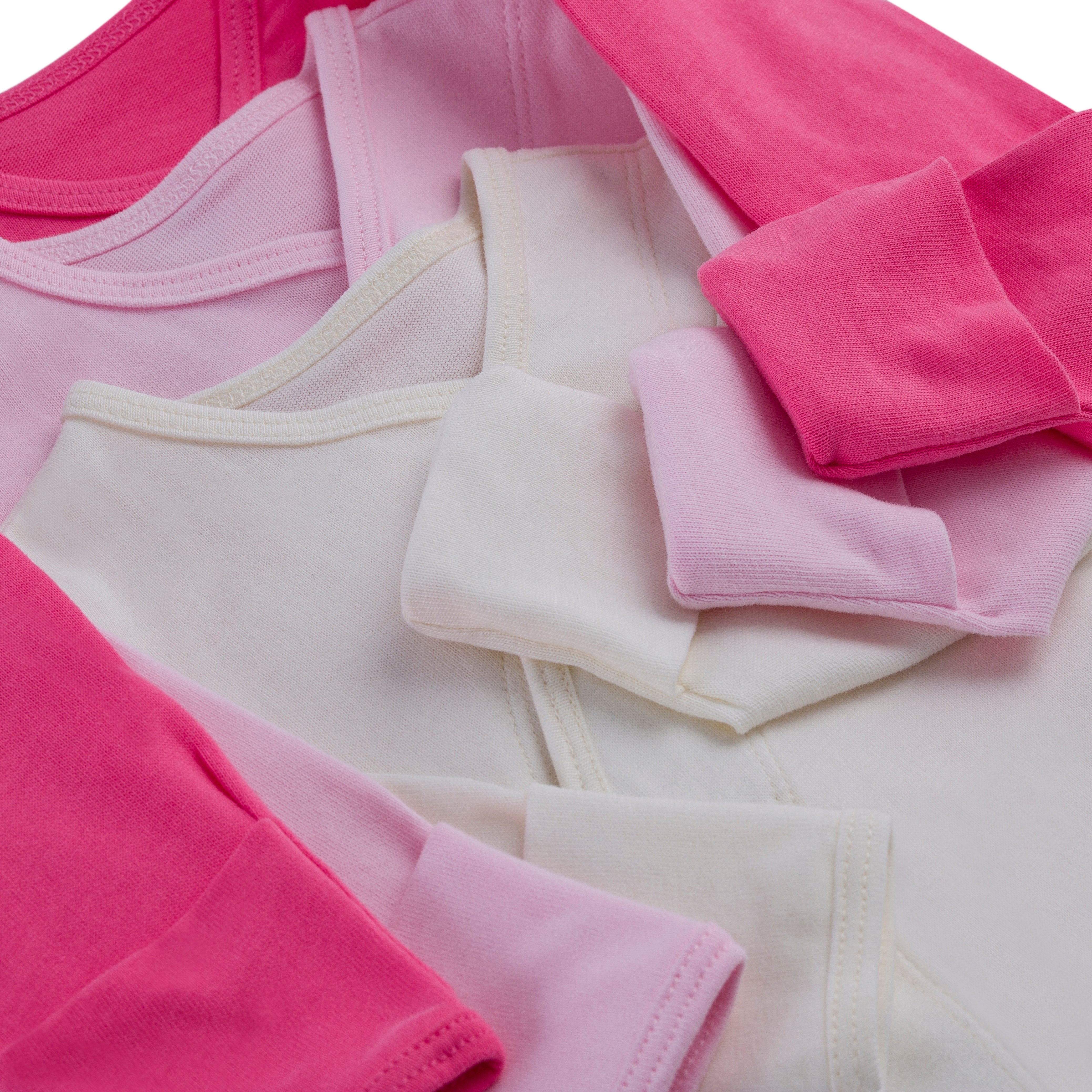 Mehrere übereinander gefaltete Baby-Bodys in Pastellrosa und Weiß.