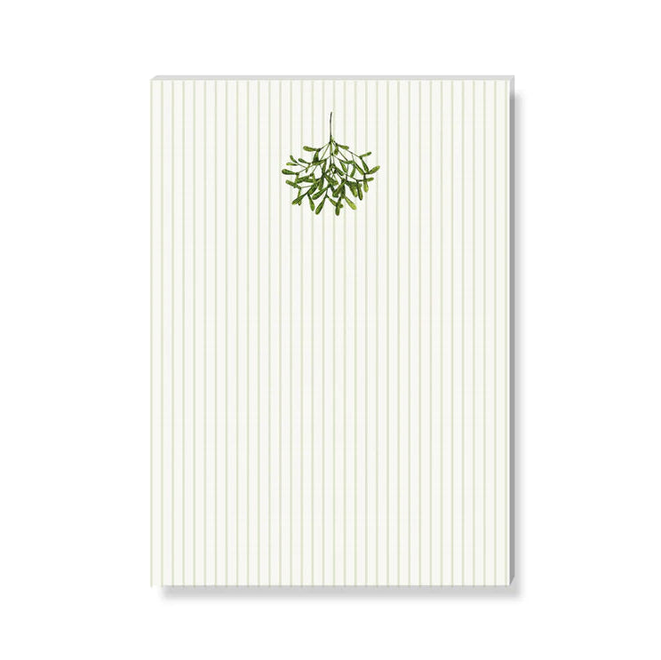 Ein vertikal gefütterter Notizblock mit einem kleinen grünen Mistelzweig, der oben in der Mitte über den Zeilen auf einem schlichten weißen Hintergrund abgebildet ist.