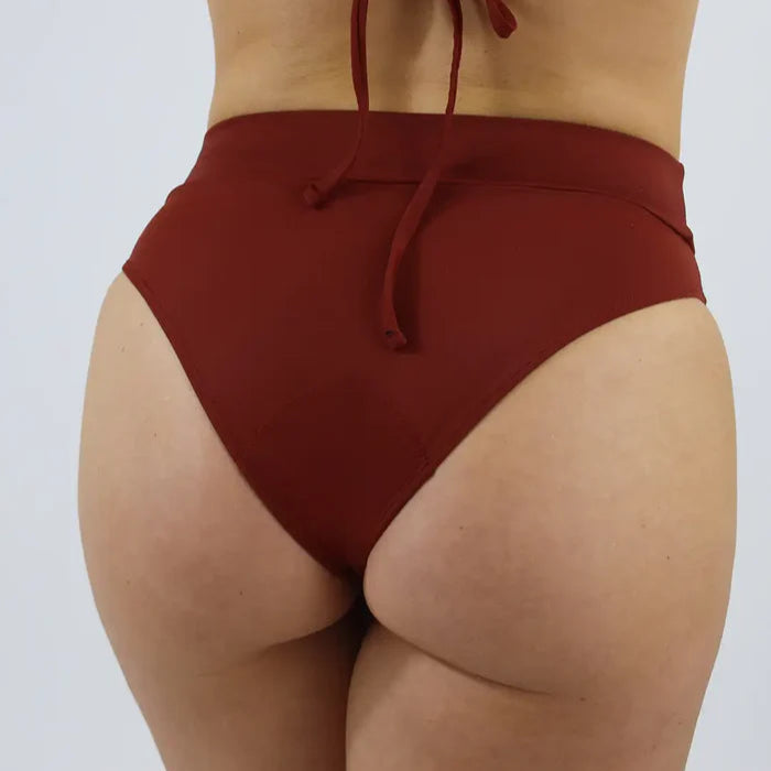 Person trägt einen hochgeschnittenen, roten Badeanzug von hinten.