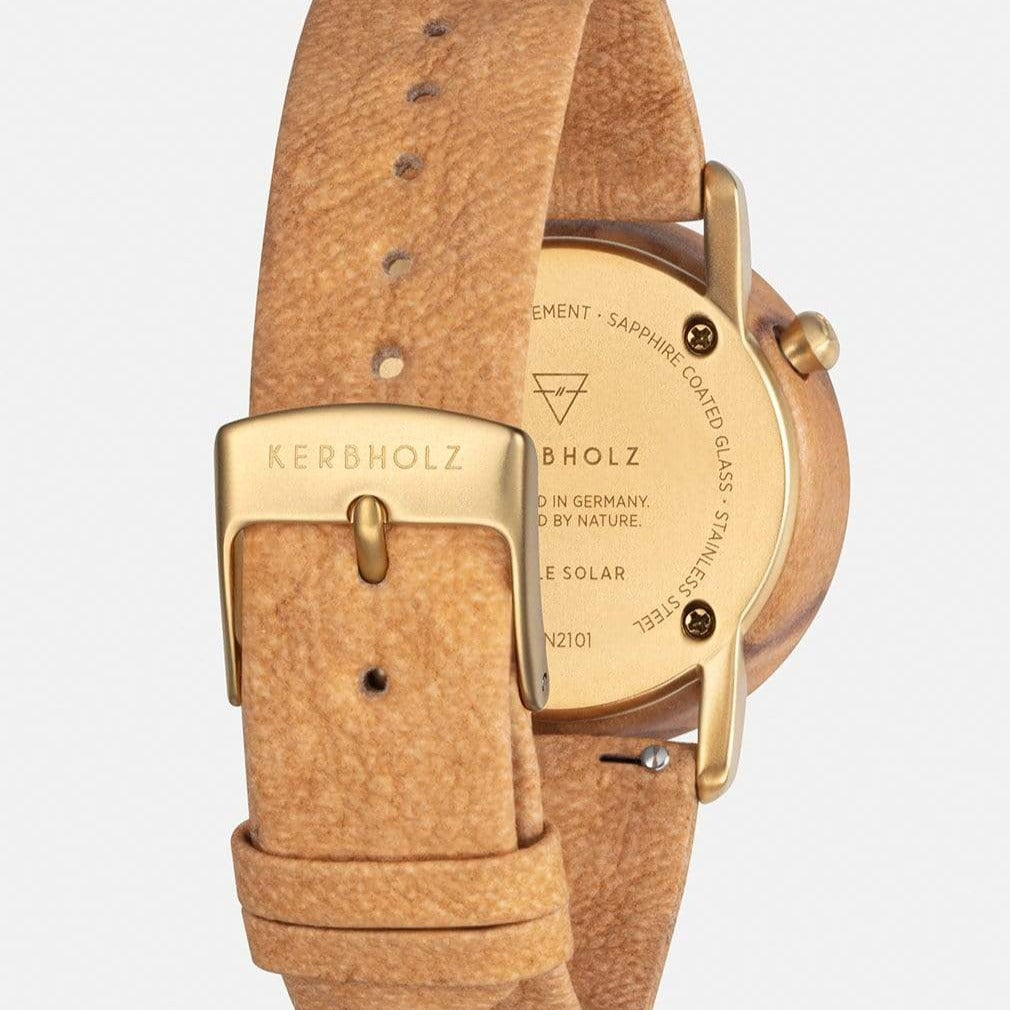 Rückansicht einer Uhr mit goldenem Gehäuse und braunem Lederarmband, das den Markennamen „Kerbholz“ zeigt.