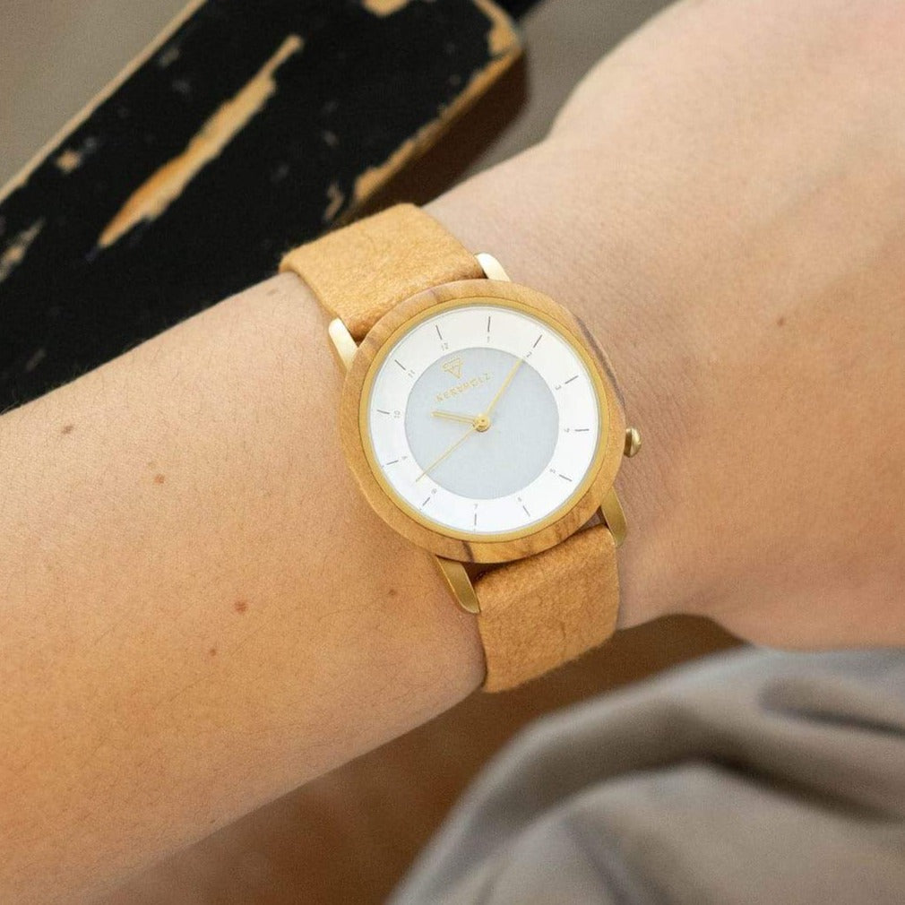 Nahaufnahme einer Holzarmbanduhr mit hellbraunem Armband auf einem Handgelenk.
