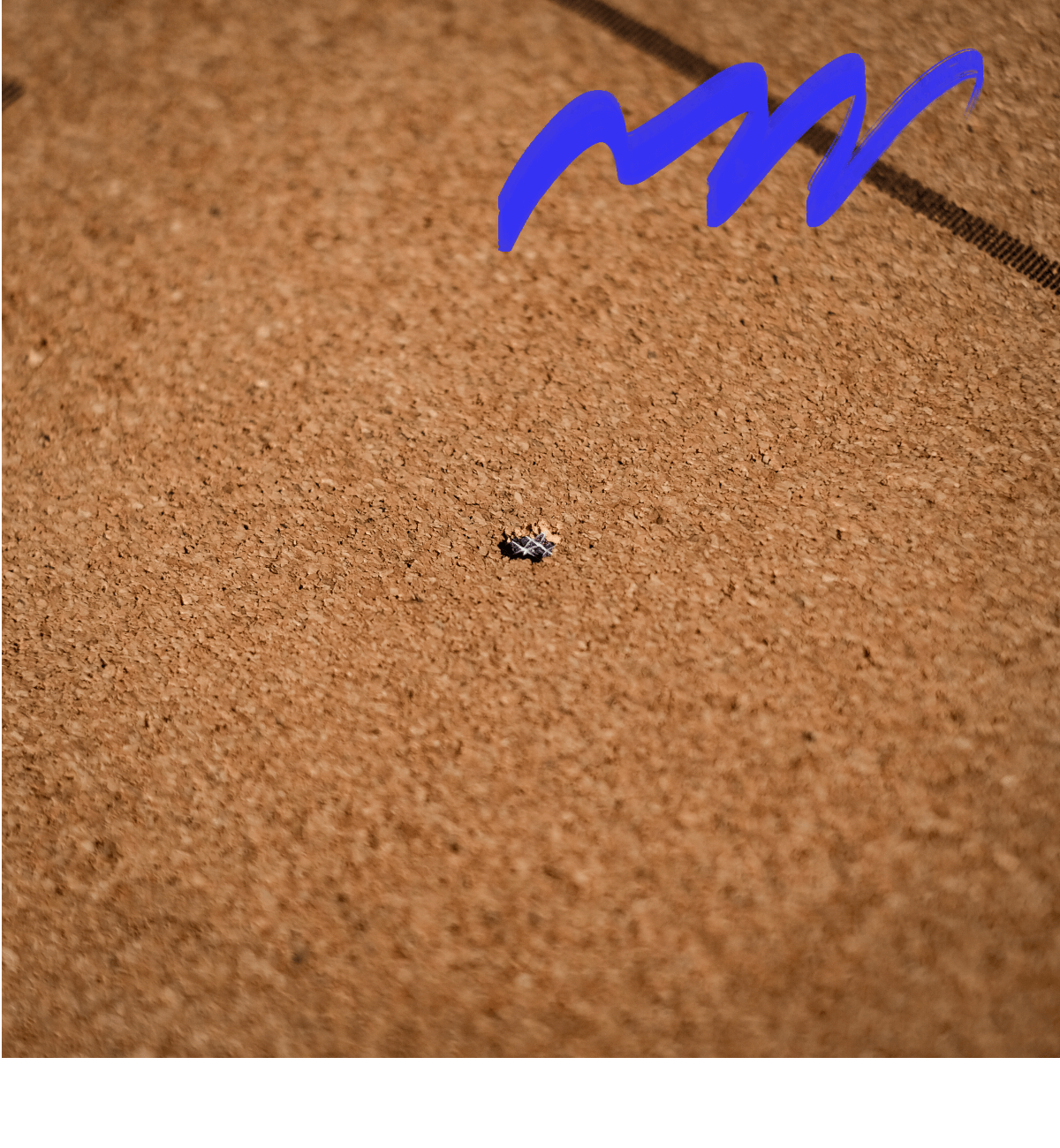 Korktafel mit einem kleinen zerknautschten Papierstück unten und einer blauen, gewellten Linie oben.