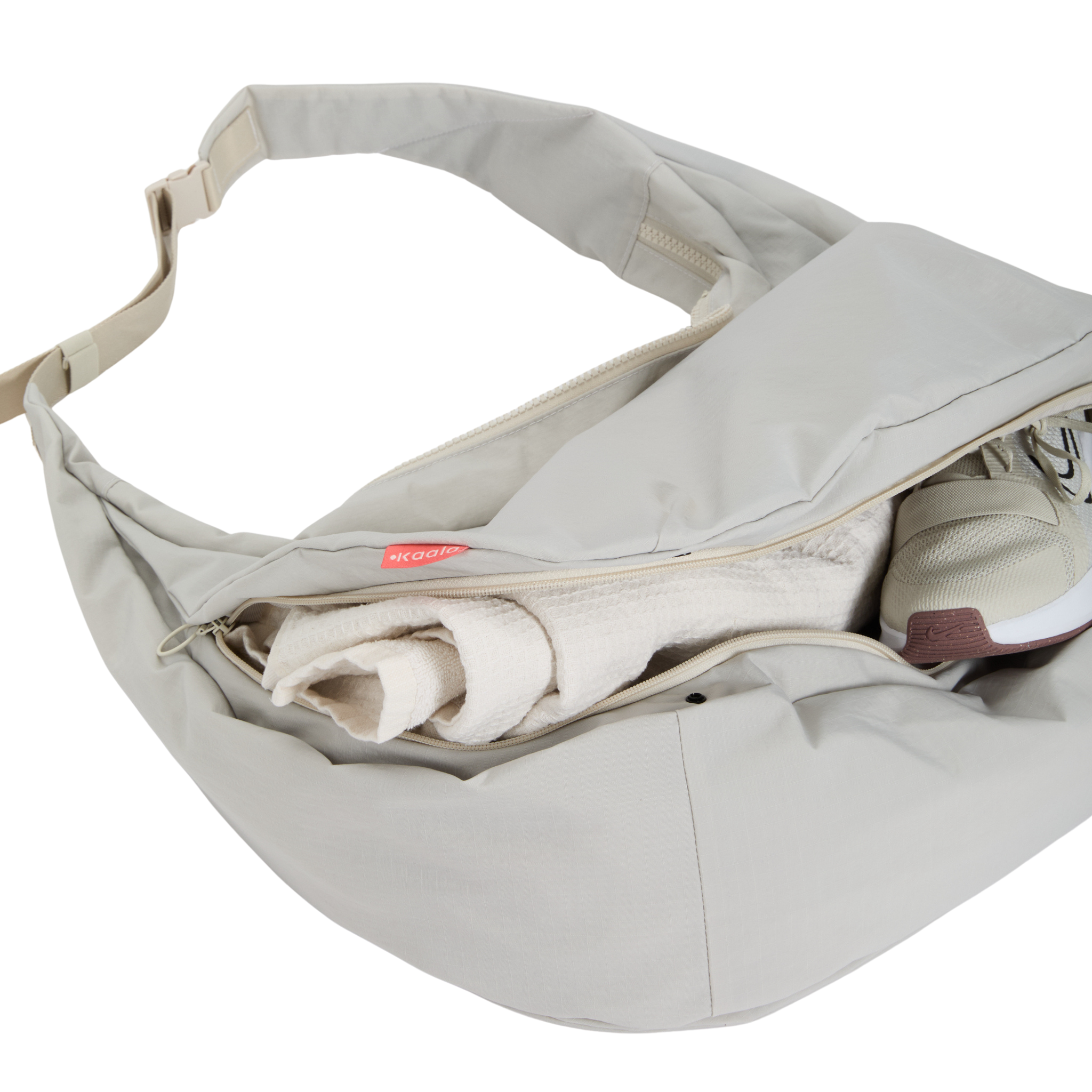 Geöffnete graue Umhängetasche mit einem Handtuch und einem Sportschuh darin.