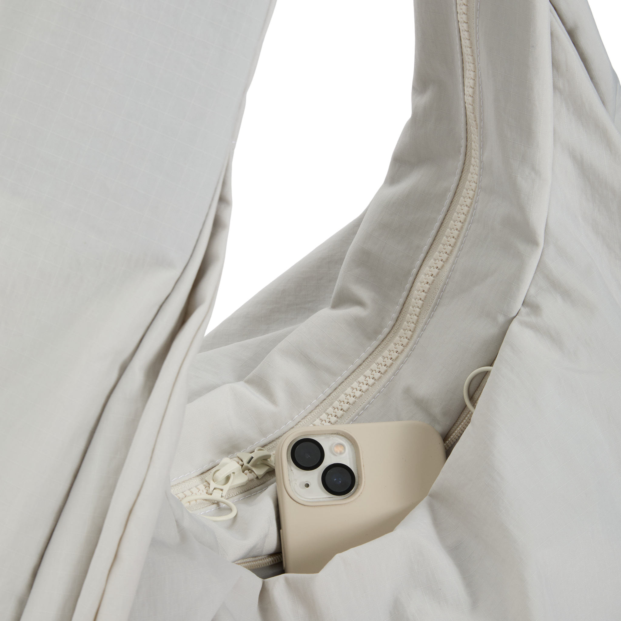 Ein beigefarbenes Smartphone steckt in der weißen Tasche eines Kleidungsstücks mit Reißverschluss.