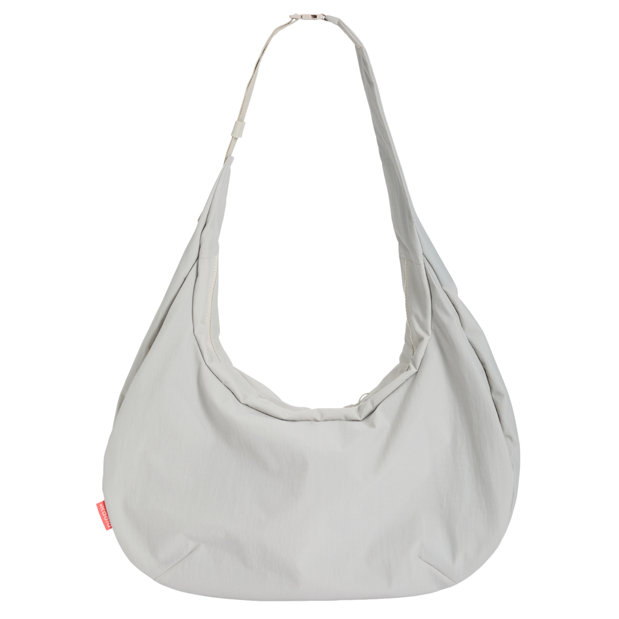 Große, helle Umhängetasche mit breitem Riemen und einem kleinen, roten Etikett an der Seite.