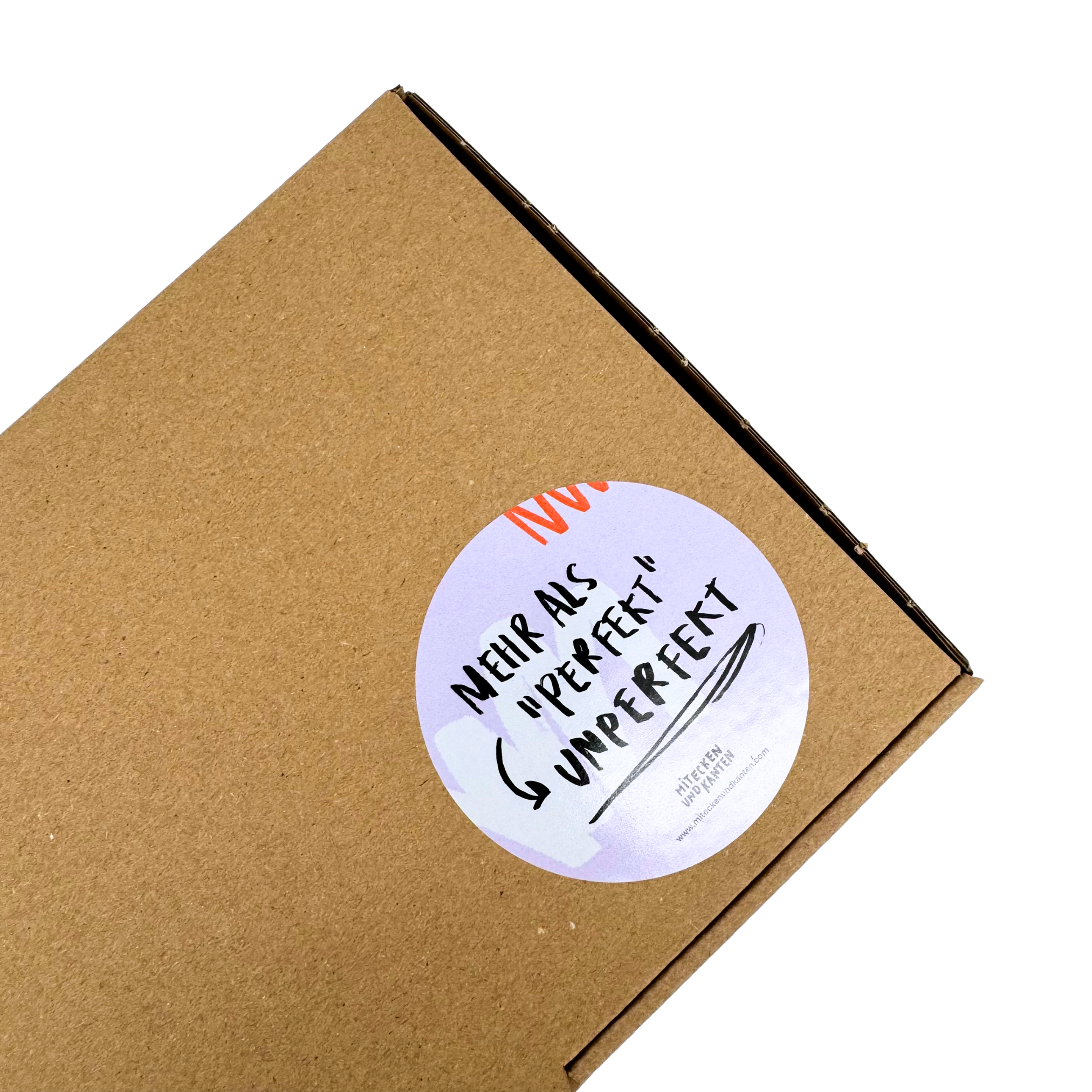 Kartonverpackung mit rundem Aufkleber, der die Aufschrift "Mehr als 'perfekt' unperfekt" in schwarzer Schrift zeigt.