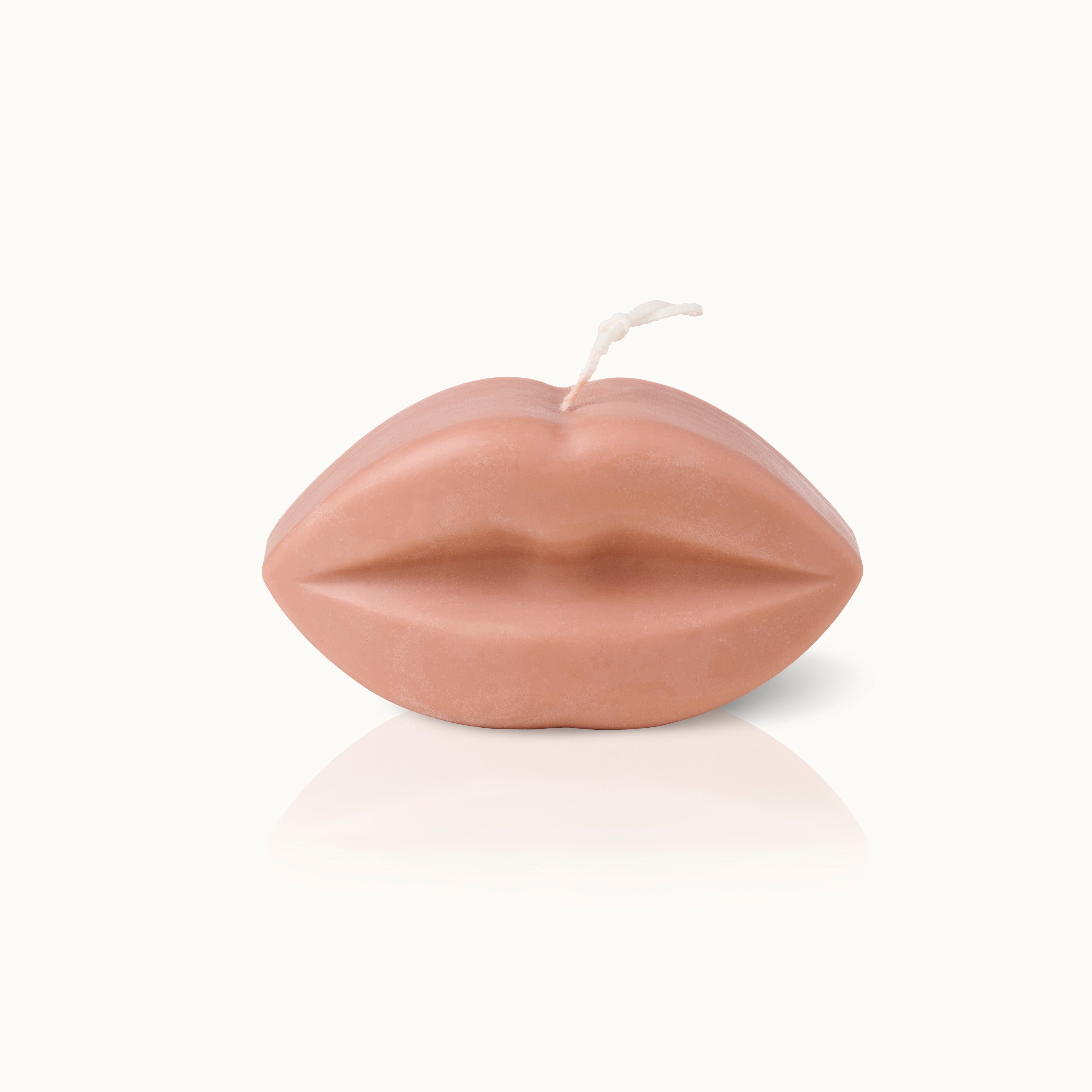 Kerze in Form von Lippen aus beigem Wachs auf weißem Hintergrund.