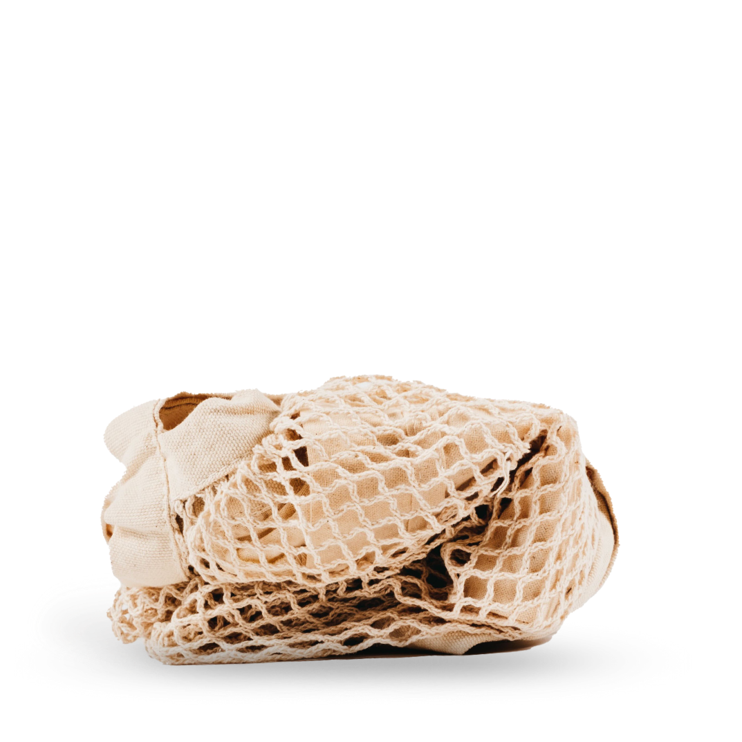 Eine beigefarbene, wiederverwendbare Einkaufstasche aus Baumwollgewebe ist auf einem weißen Hintergrund ordentlich gefaltet.
