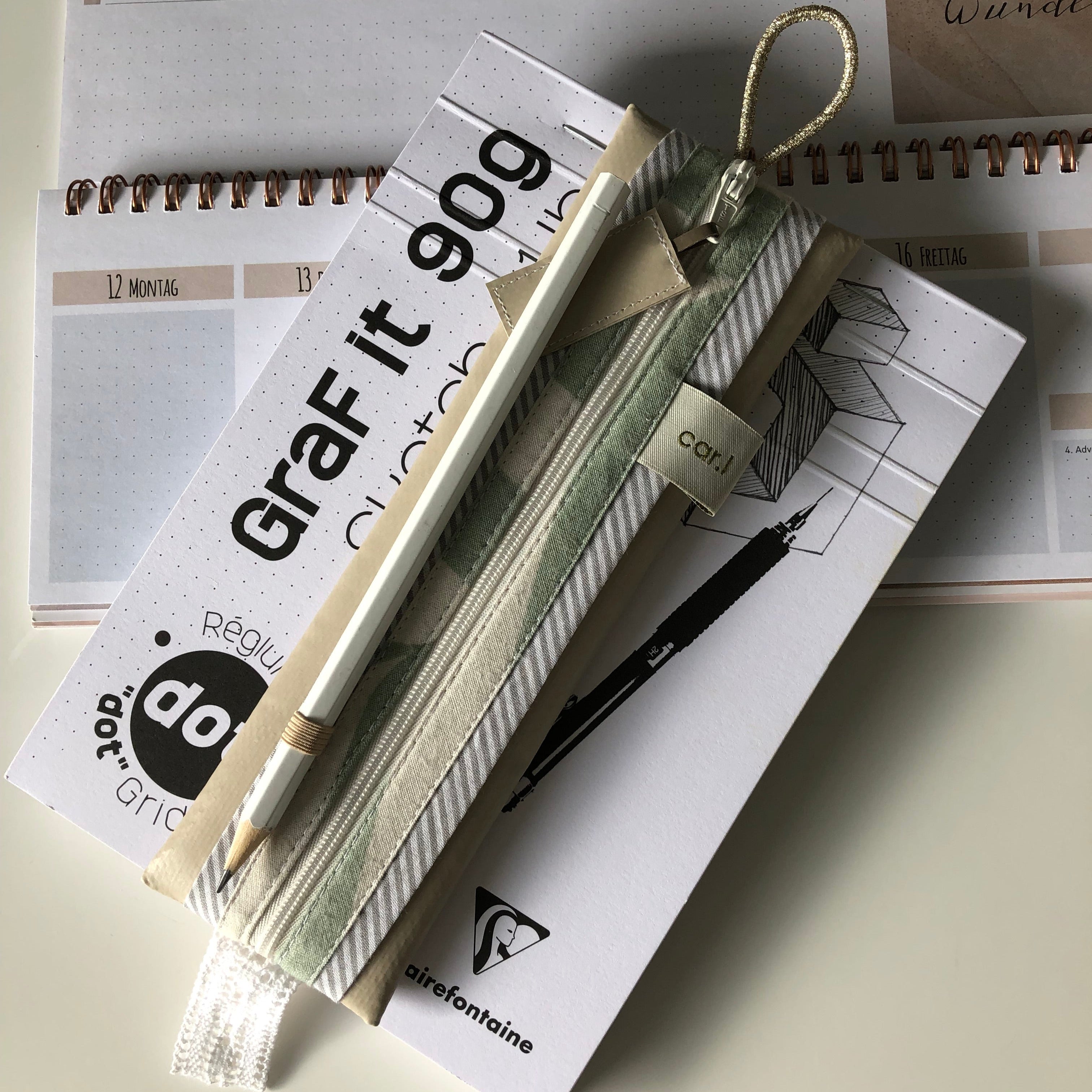 Kalender und Notizblock mit Federmäppchen und Stift darauf, aus einer senkrechten Perspektive fotografiert.