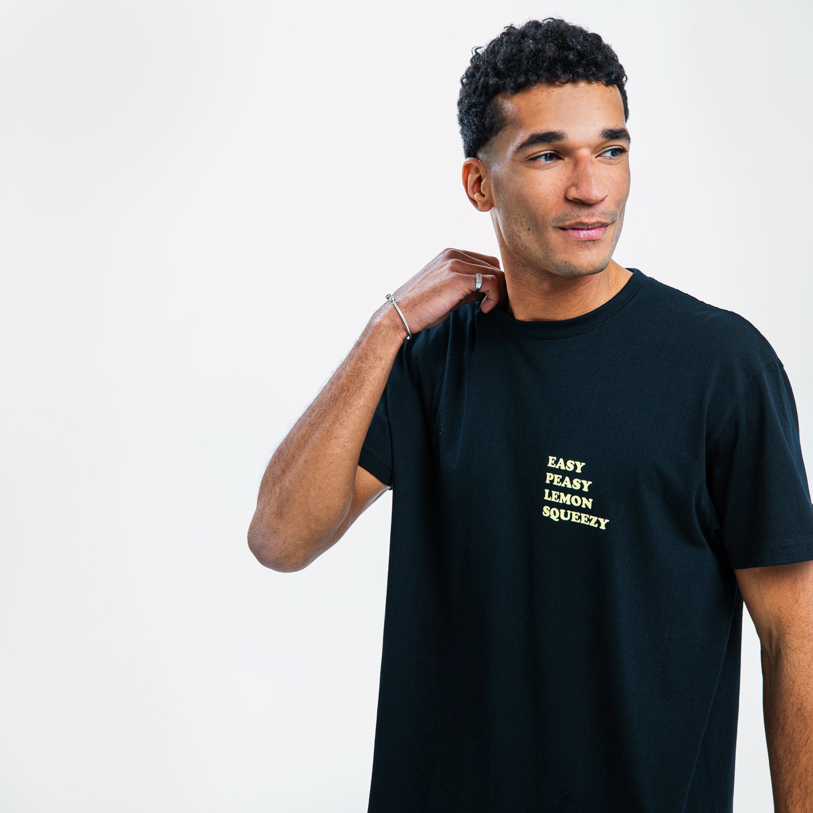 Ein Mann in einem schwarzen T-Shirt mit der Aufschrift "Easy Peasy Lemon Squeezy" schaut zur Seite.