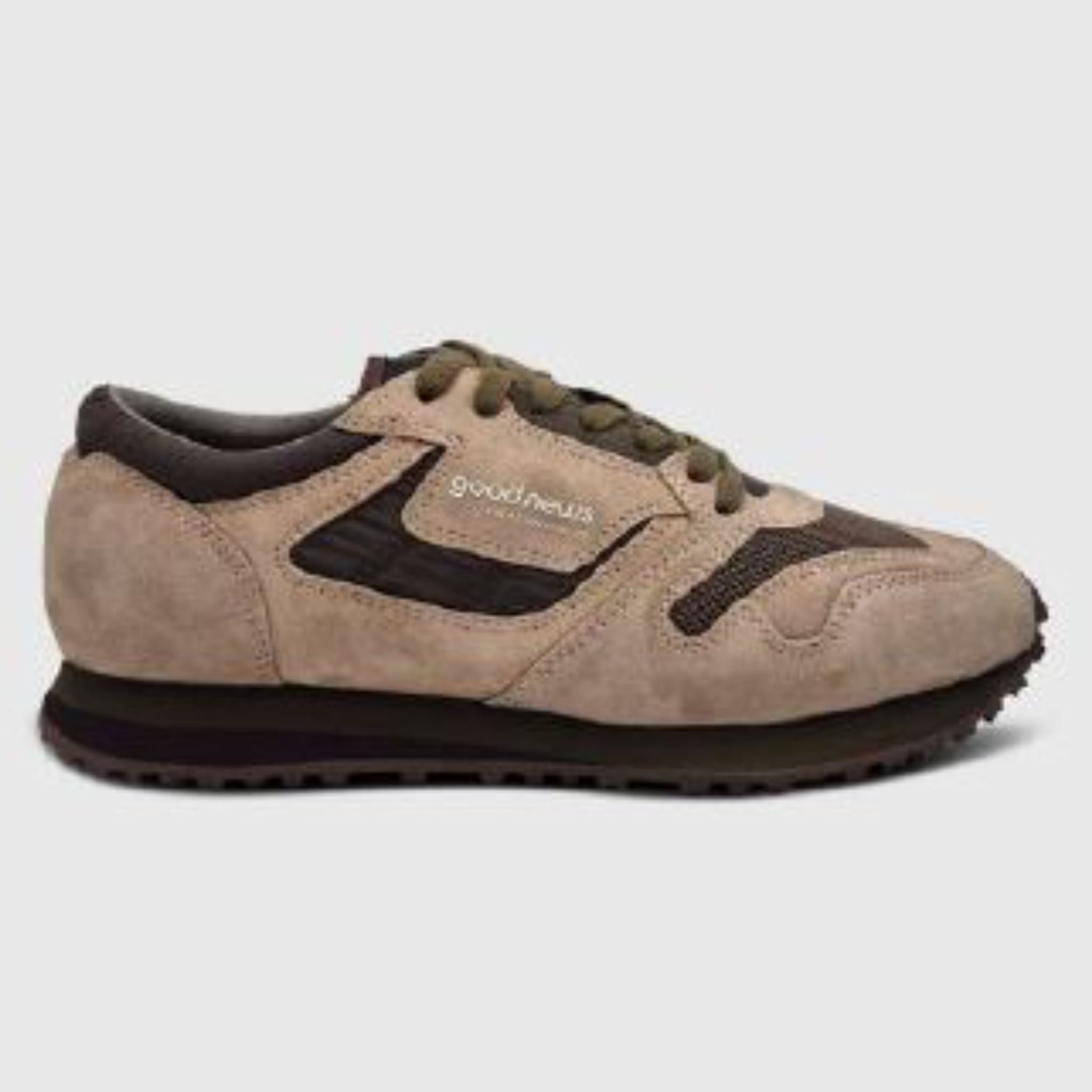 Ein beiger und brauner Wildleder-Sneaker mit dunkelbraunen Akzenten, olivgrünen Schnürsenkeln, einer schwarzen Laufsohle und dem aufgedruckten Markennamen Good News auf einem hellgrauen Hintergrund.