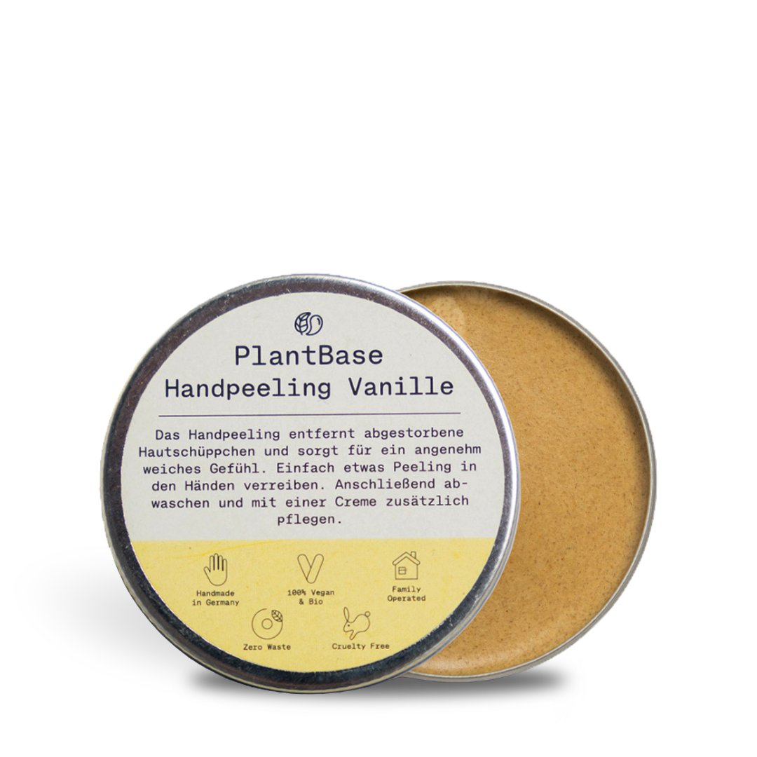 Ein runder Dosenbehälter mit PlantBase Handpeeling Vanille, dessen Deckel teilweise geöffnet ist und ein beigefarbenes Peeling enthüllt. Das Etikett beschreibt das Produkt auf Deutsch und hebt es als vegan, tierversuchsfrei und handgemacht hervor.