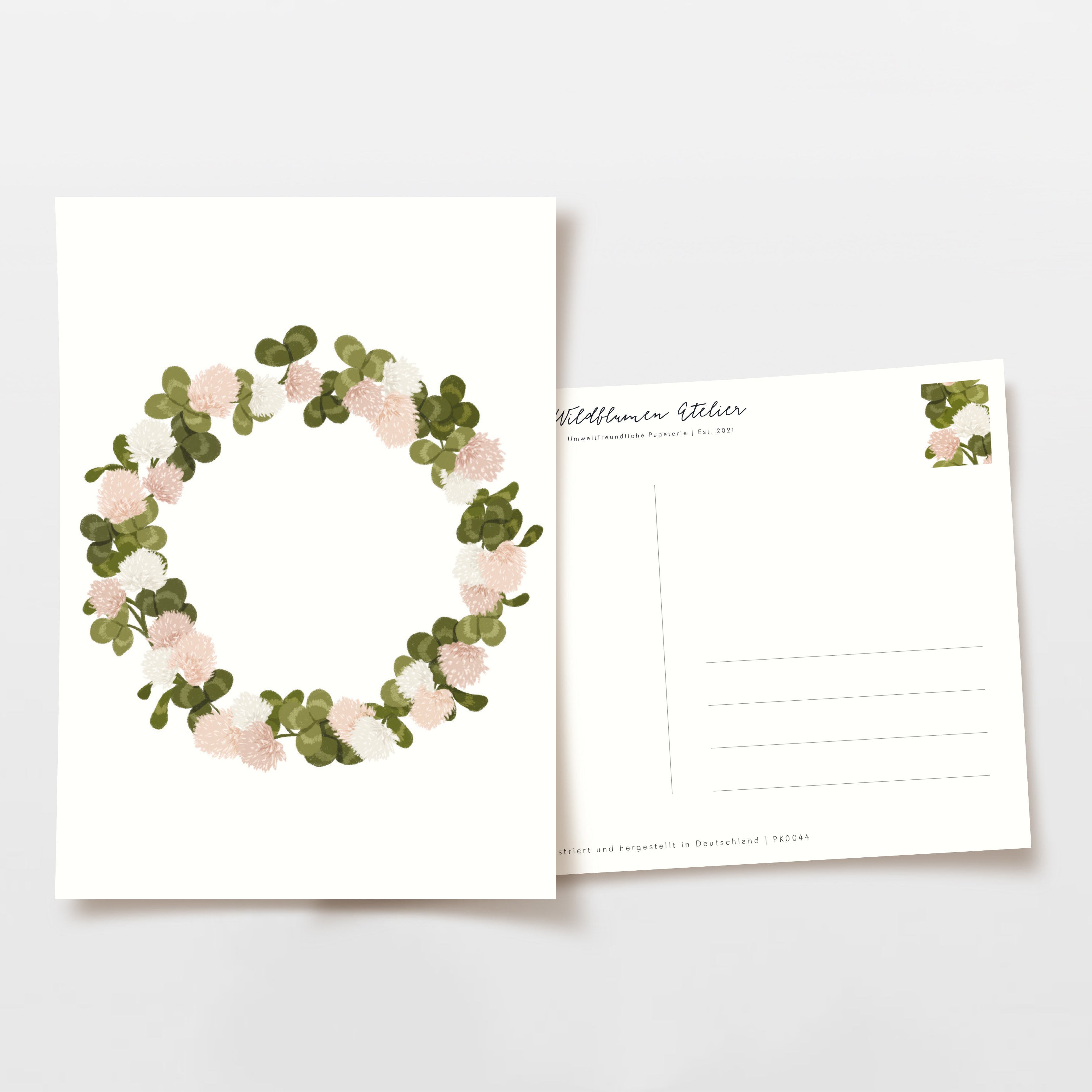 Zwei Postkarten, eine mit blumigem Kranzmuster und die andere mit Linien für eine Adresse, nebeneinander liegend.