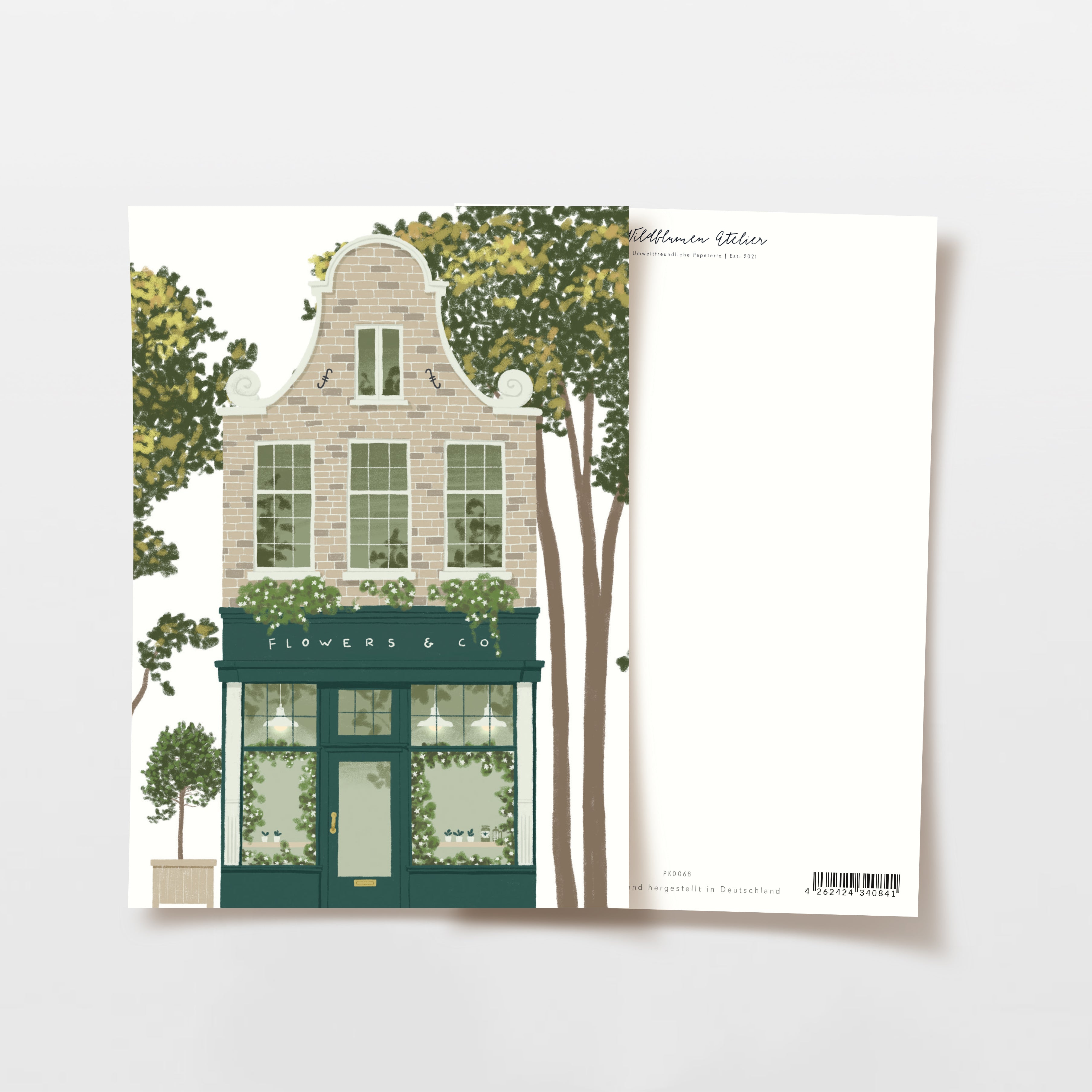 Illustration einer Postkarte, die ein charmantes, gemauertes Blumengeschäft mit großen Fenstern, grünen Akzenten, Topfpflanzen und umliegenden Bäumen zeigt. Die Rückseite der Postkarte ist leer, außer für minimale Druck am oberen und unteren Rand.