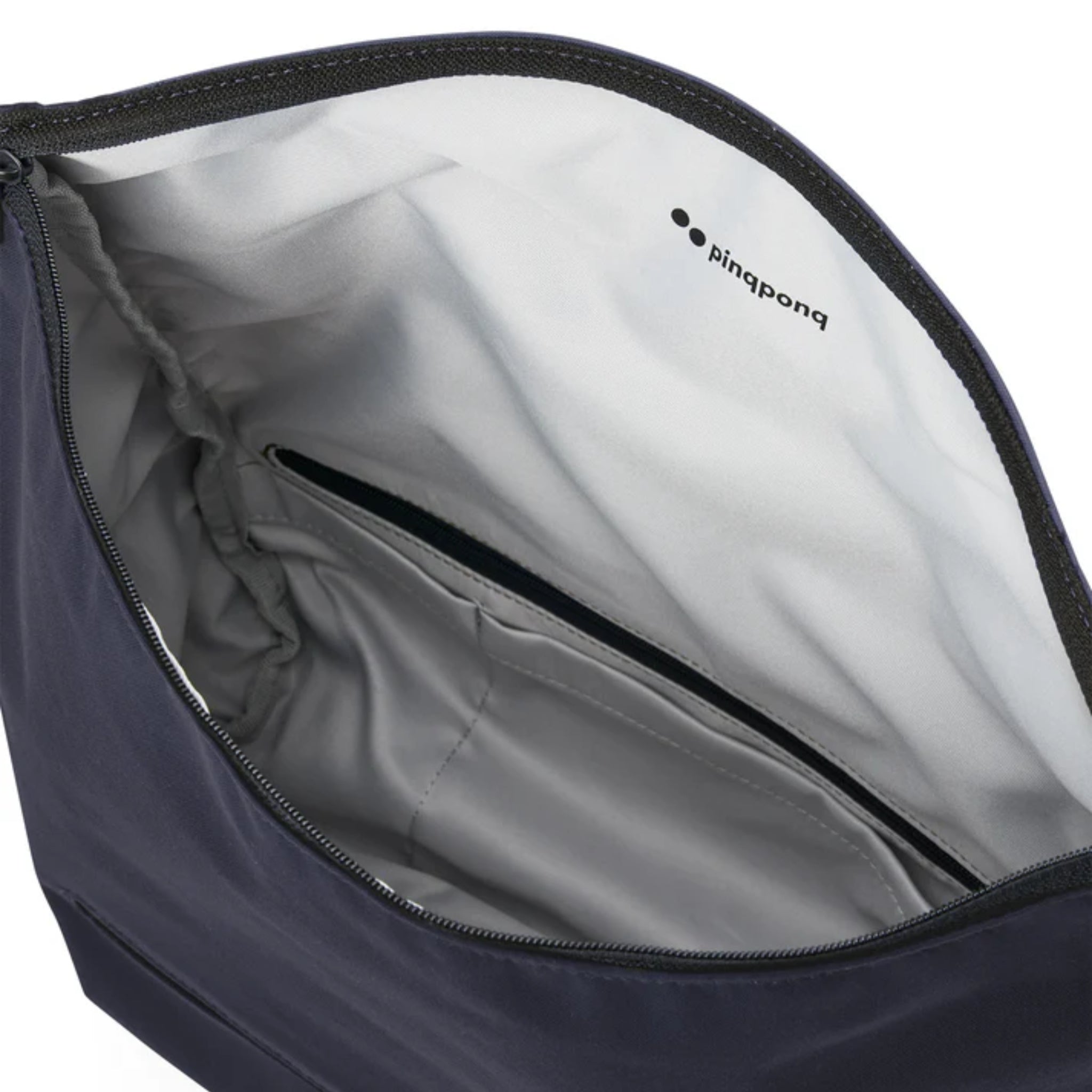 Nahaufnahme der Innenseite einer dunklen Reißverschlusstasche, die einen hellgrauen Innenraum mit einer kleinen Innentasche und das Wort "Pingpong" auf dem Futter zeigt.