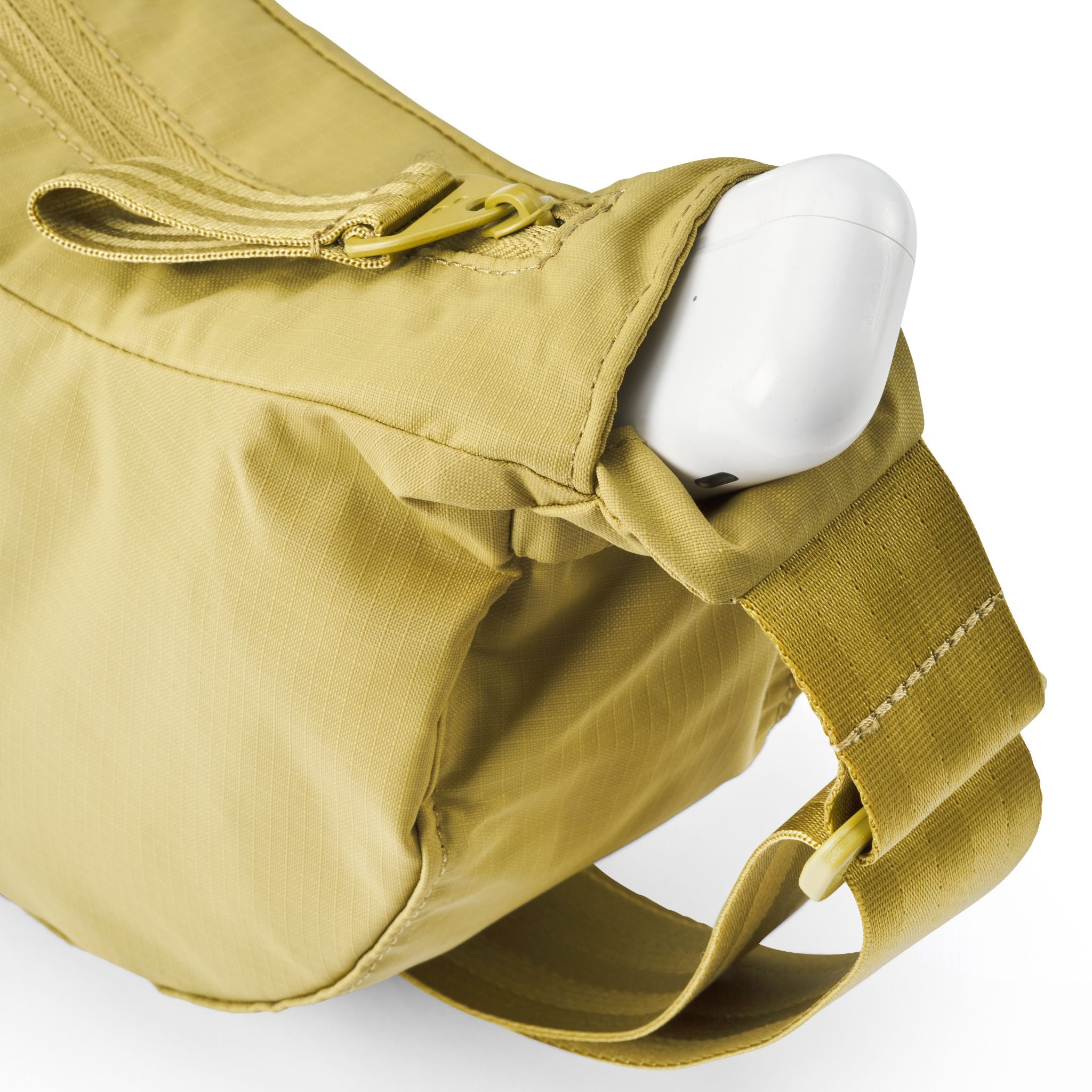 Beige Umhängetasche mit Reißverschluss, aus der ein weißer Gegenstand hervorschaut.