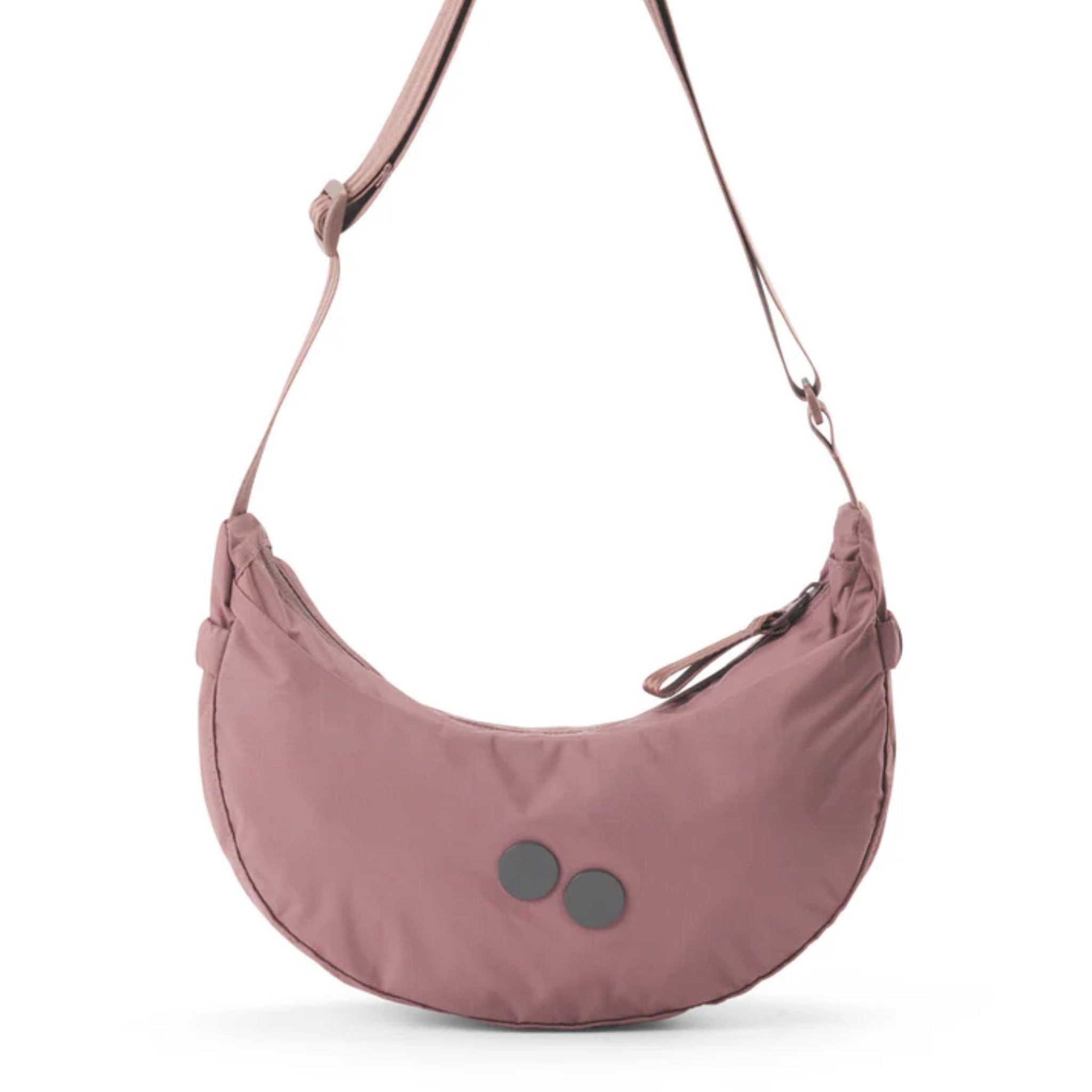 Mauvefarbene halbmondförmige Umhängetasche mit verstellbarem Riemen und zwei runden schwarzen Aufnähern auf der Vorderseite. Die Tasche wird oben mit einem Reißverschluss geschlossen.