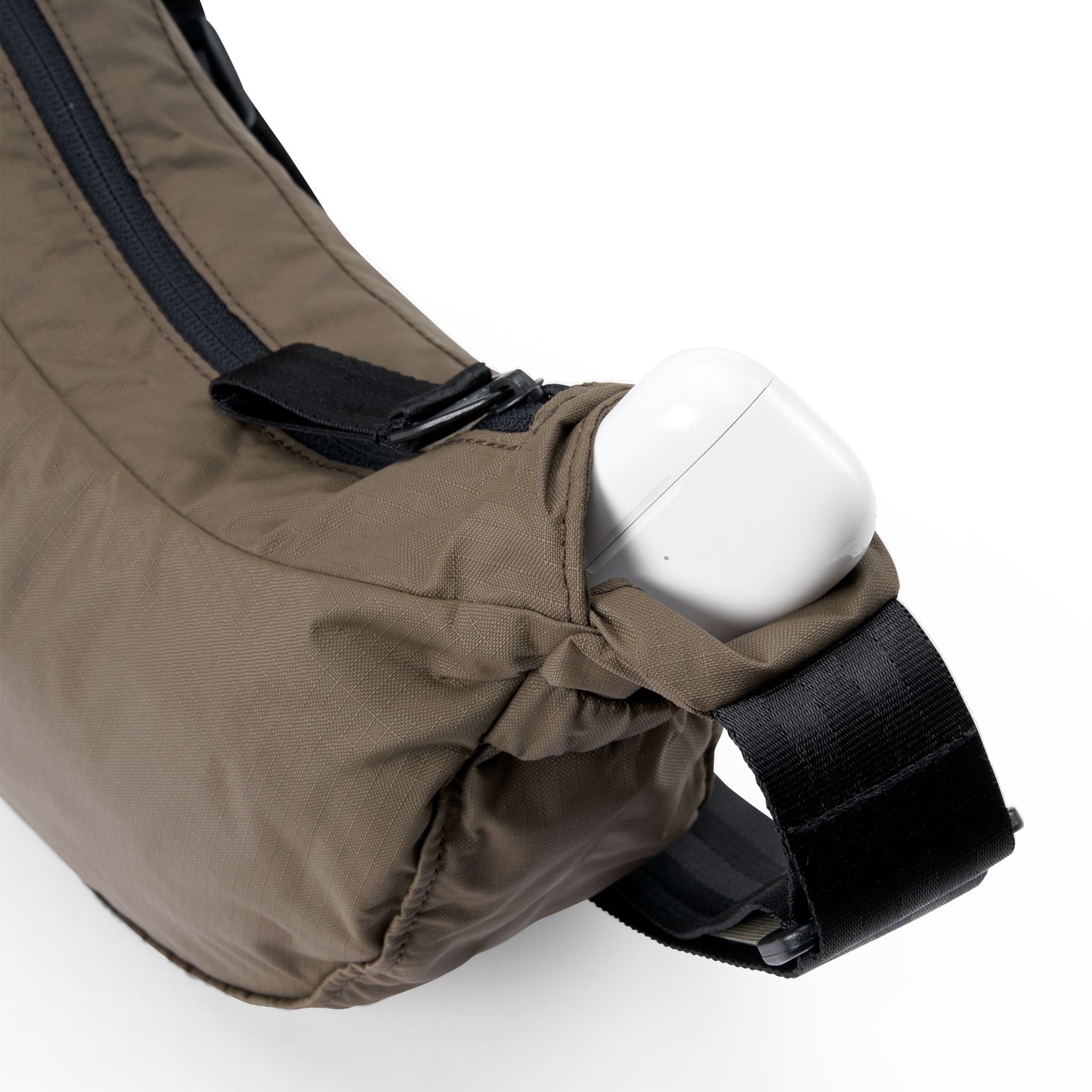 Nahaufnahme einer braunen Tasche mit einem weißen kabellosen Ohrhörer-Gehäuse in einer Seitentasche.